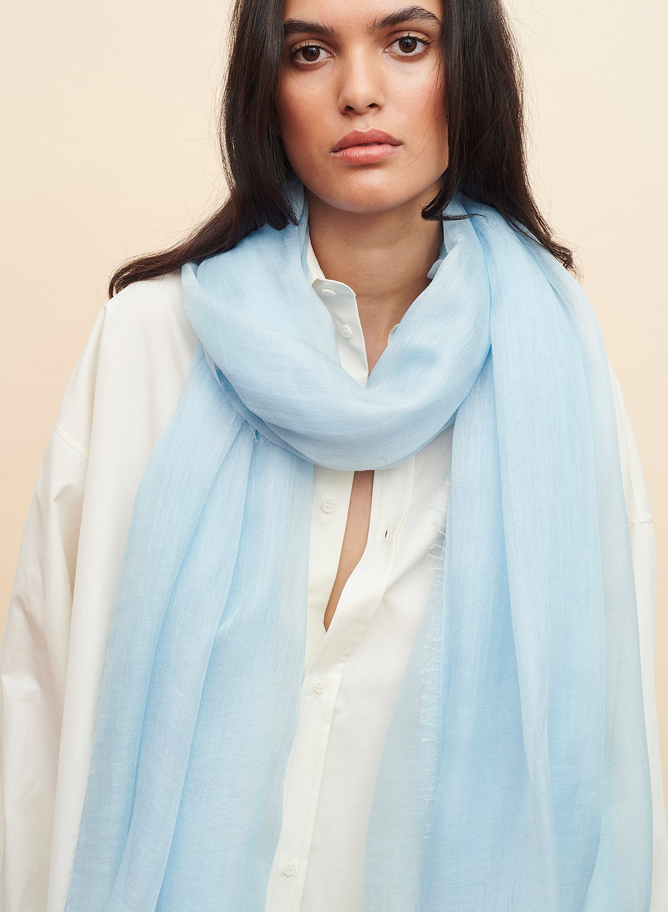 Woman wearing a light blue scarf on a beige background