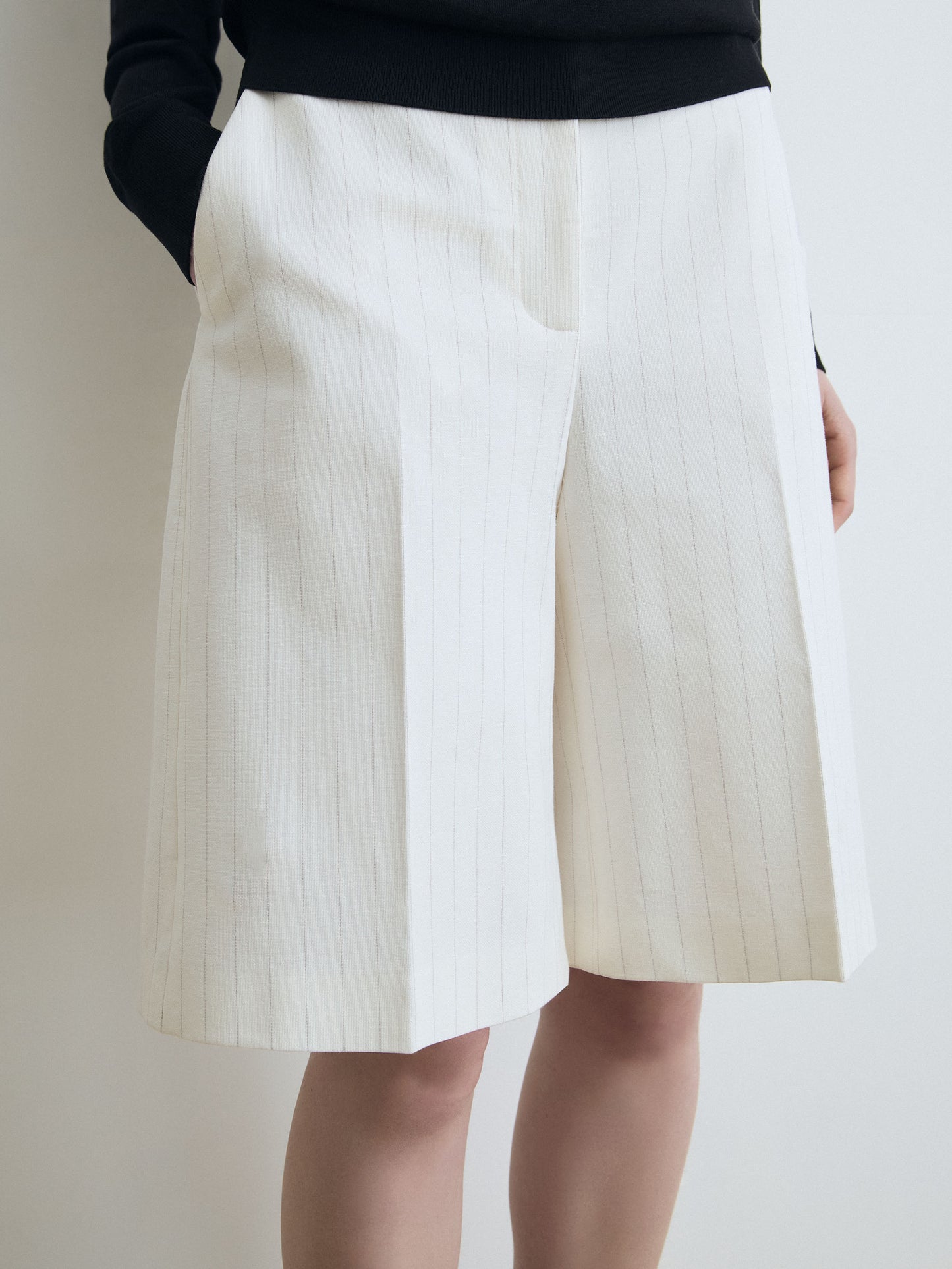 White pleated short worn by a person on a plain background