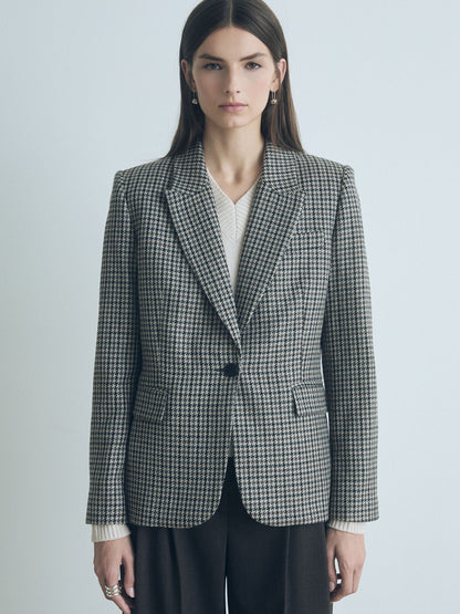 Model wearing the Judith and Charles Verne jacket in grey taupe houndstooth, featuring a tailored fit with peak lapel, front flap pockets, and single-button closure. Styled with matching trousers for a polished, modern look. Made in Canada from a fine Italian wool, silk, and linen blend