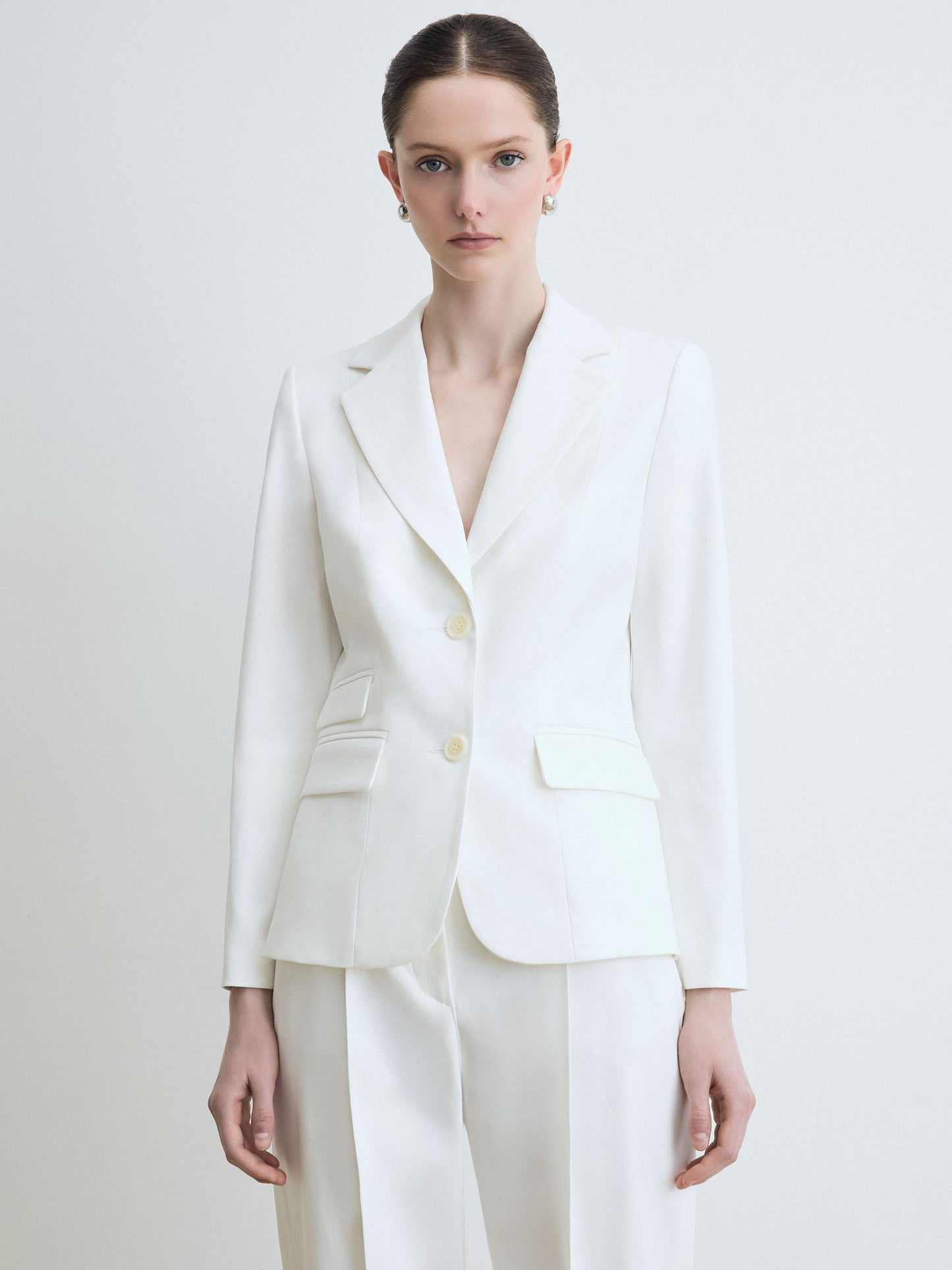 Woman wearing a white suit on a plain background