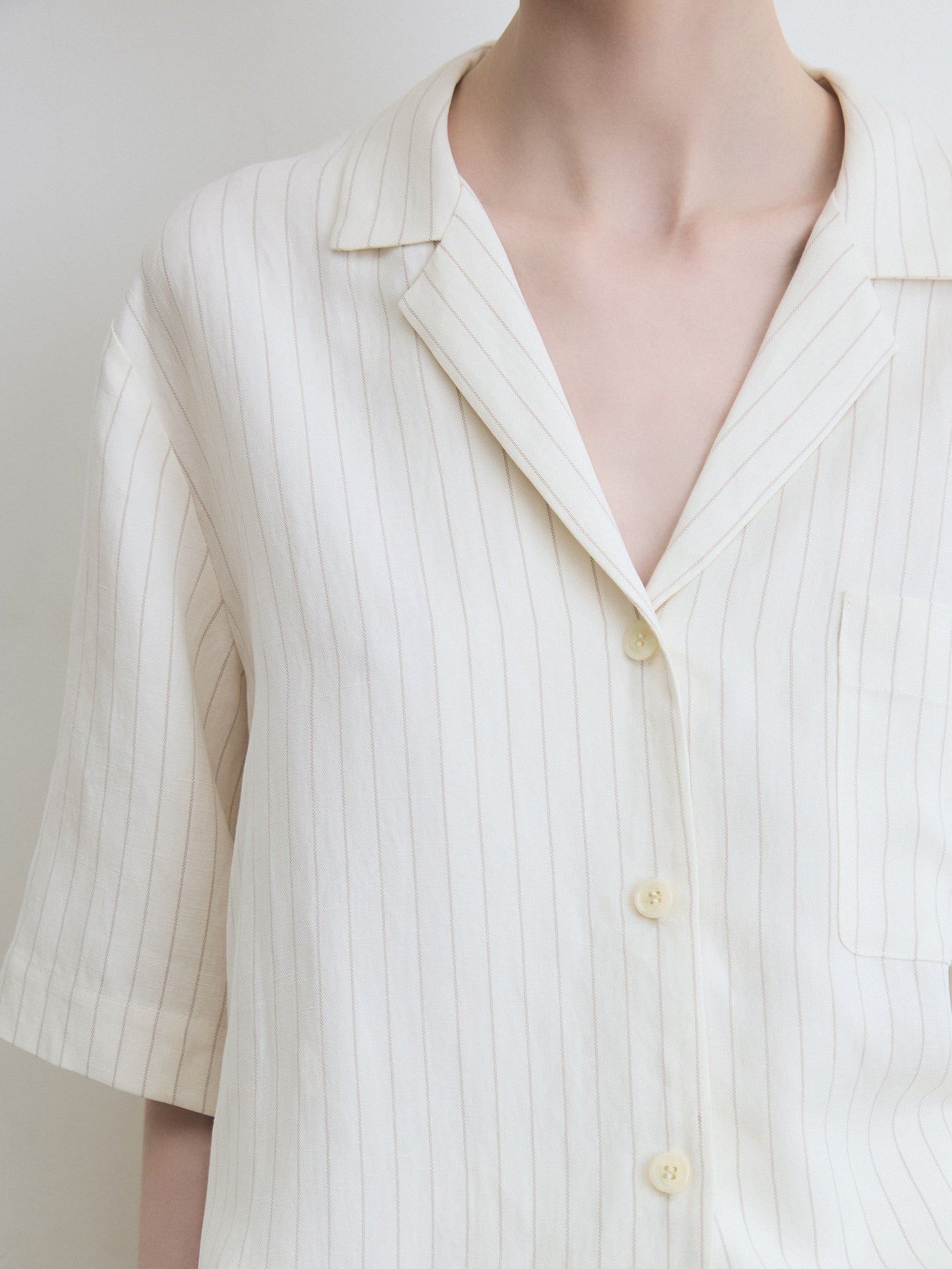 White striped shirt with short sleeves on a mannequin against a white background
