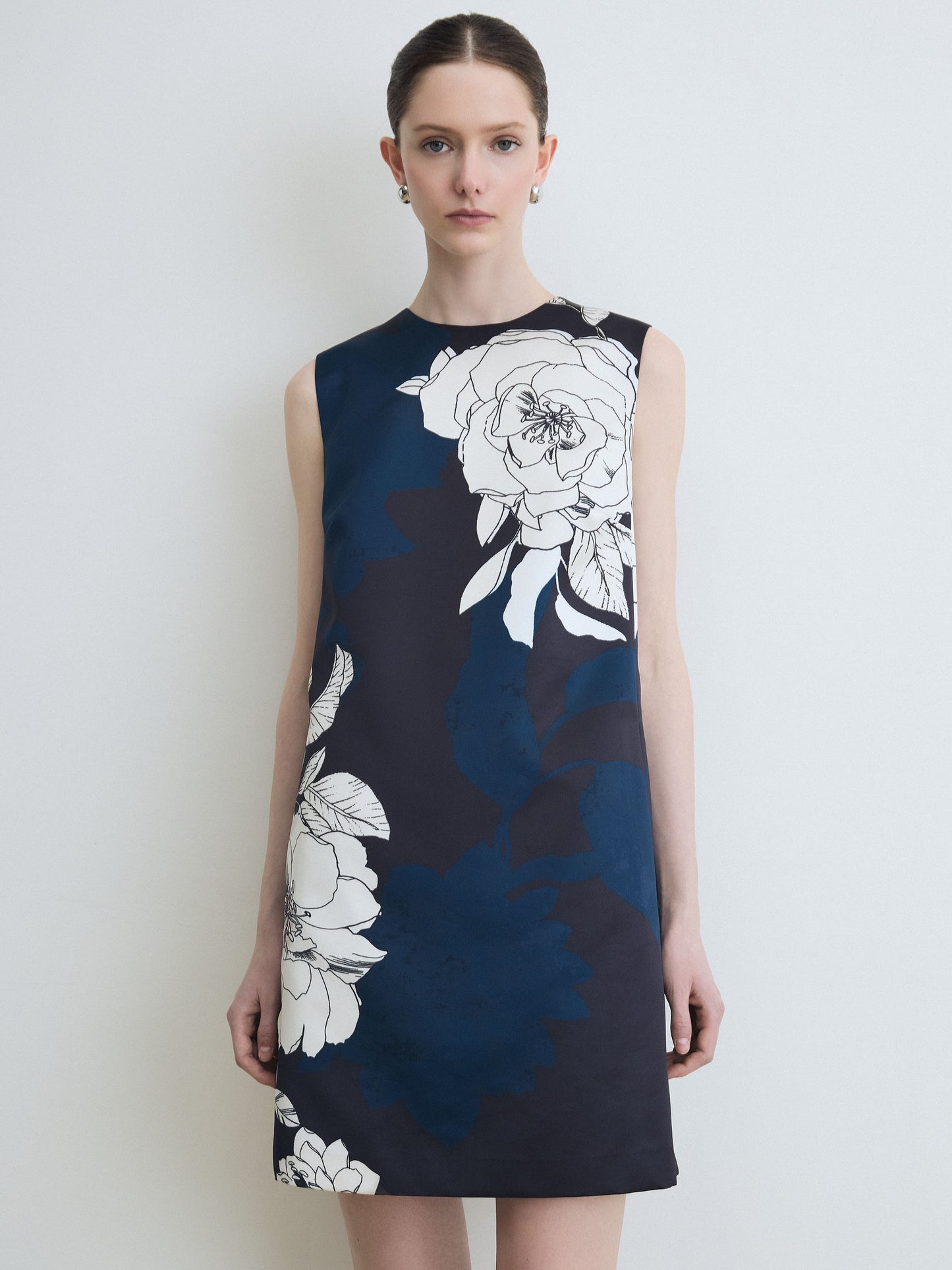 Woman wearing a navy dress with white floral patterns on a plain background