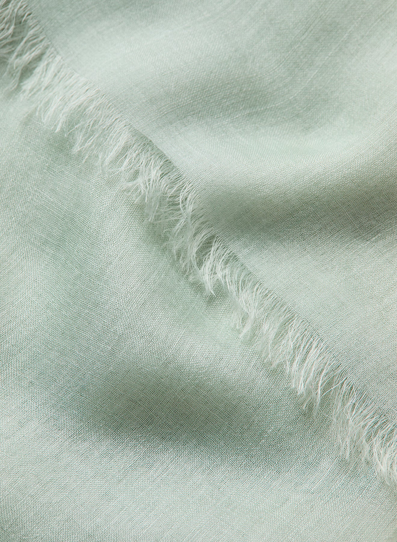 Close-up of light green fabric with frayed edges