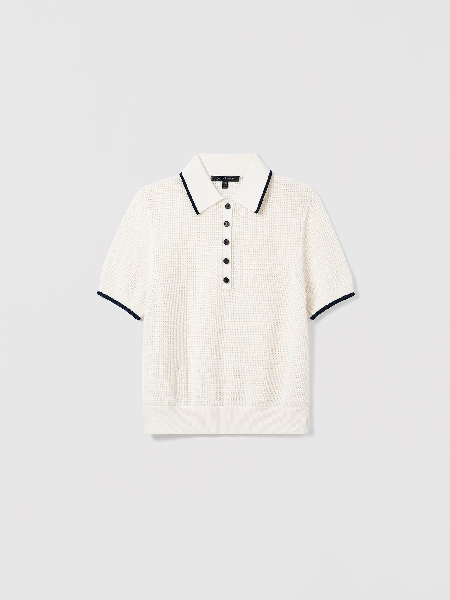 White sweater polo with navy trim on a light gray background