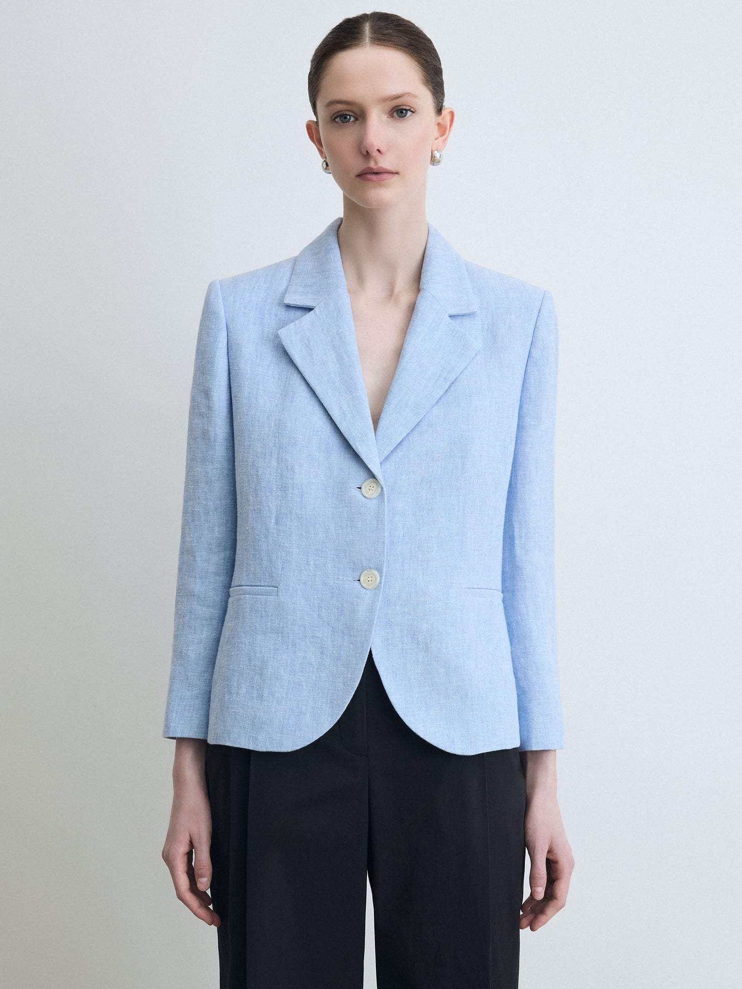 Woman wearing a light blue blazer with a plain background