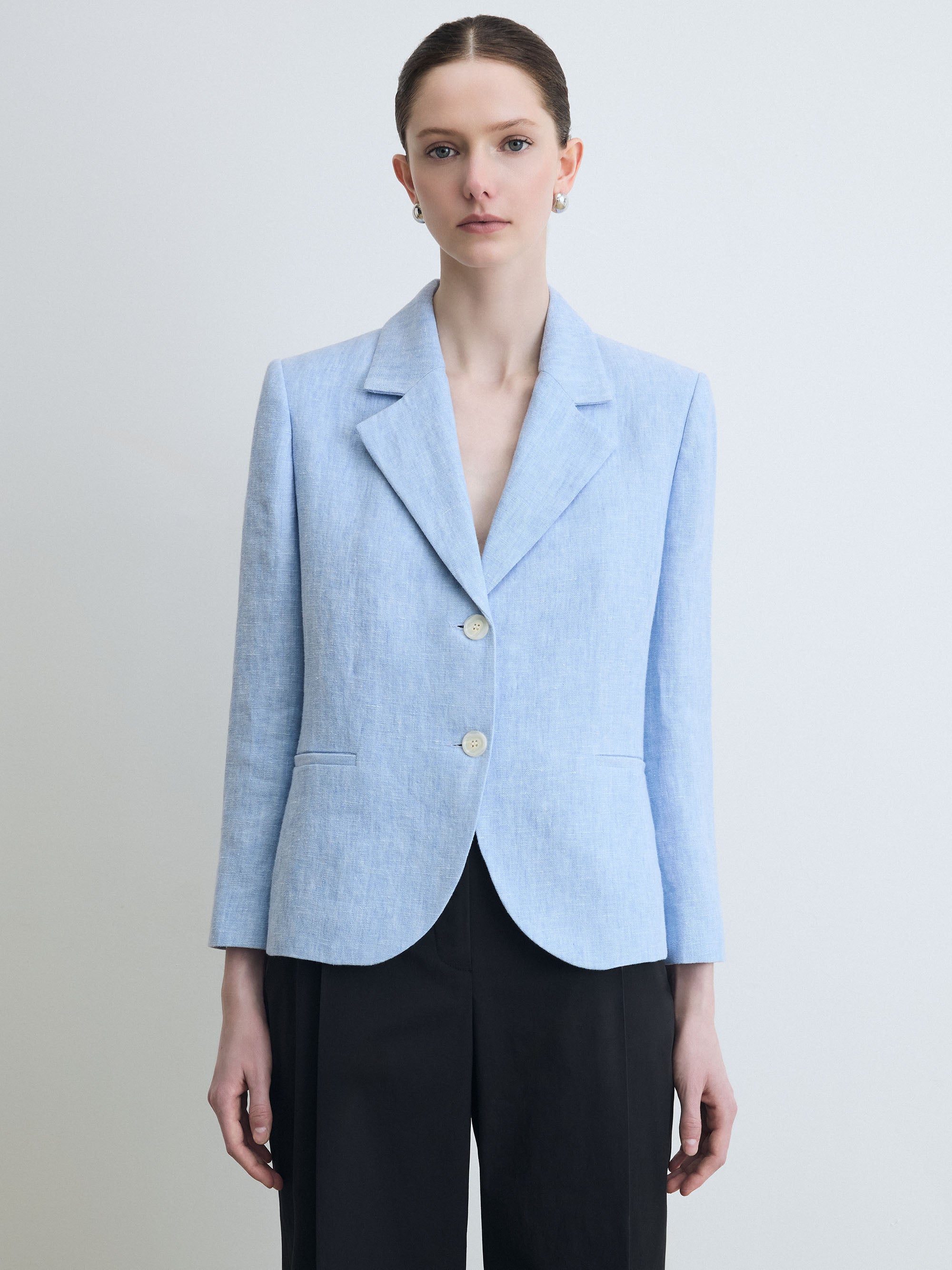 Woman wearing a light blue blazer with a plain background
