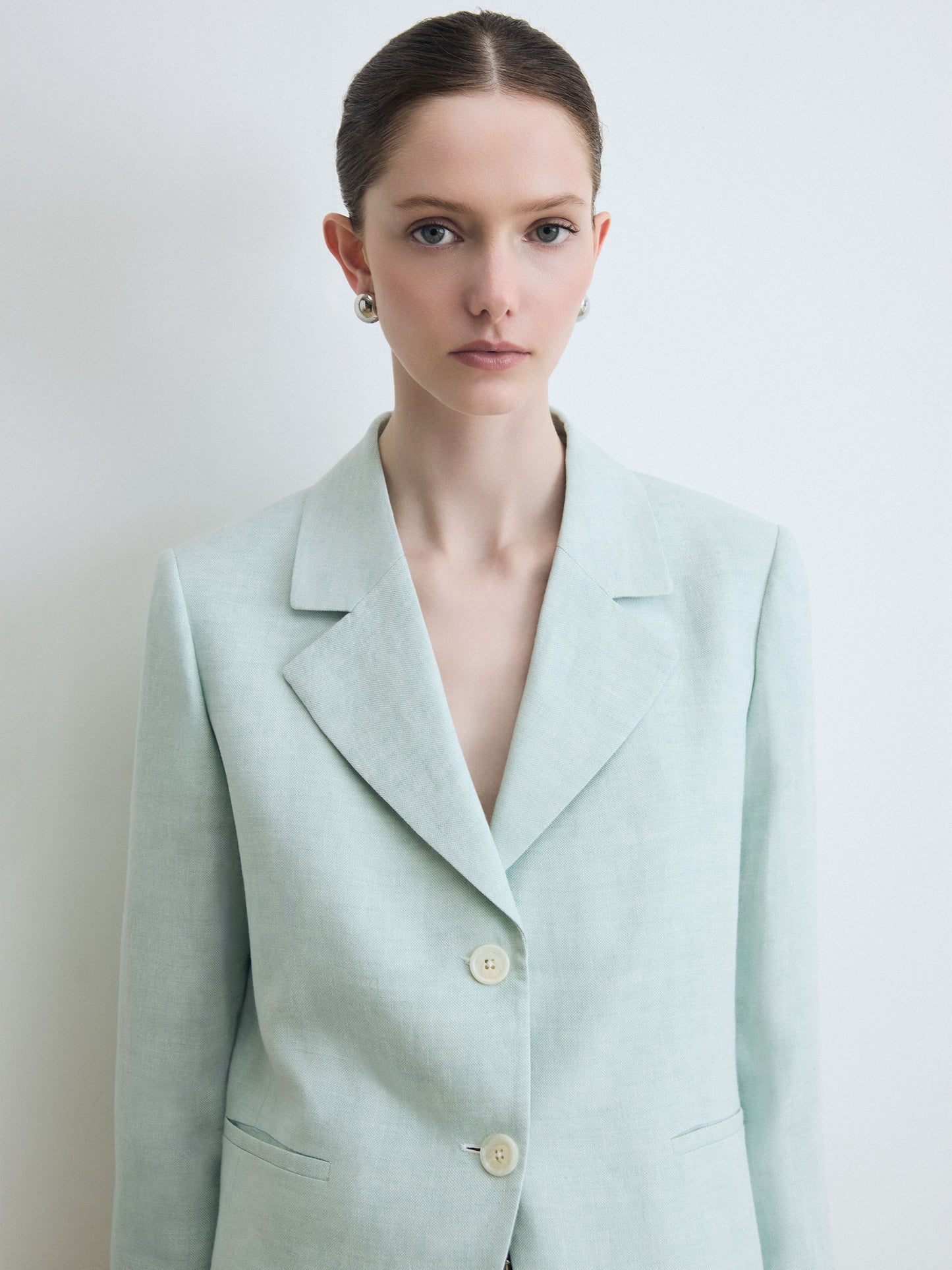 Woman wearing a light green blazer against a plain background