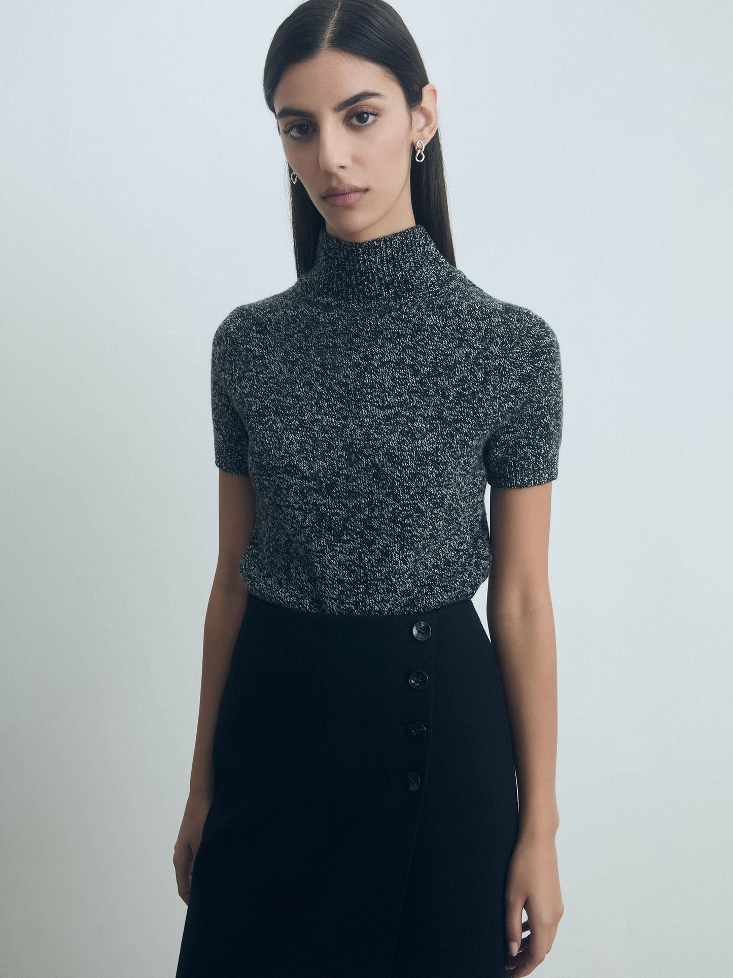 Woman wearing a fitted short sleeve mock neck sweater in extrafine Italian wool, color Black/Off White by Judith and Charles sweater with a plain background