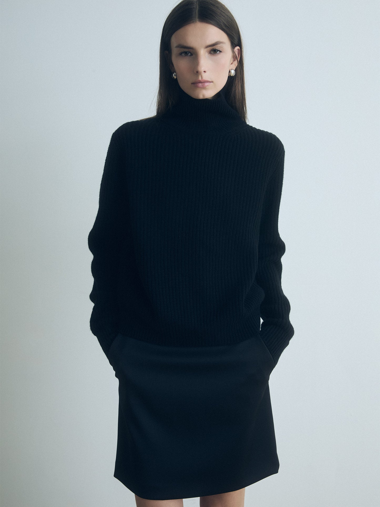 Model wearing a judith and charles black turtleneck and dark pants against a plain background