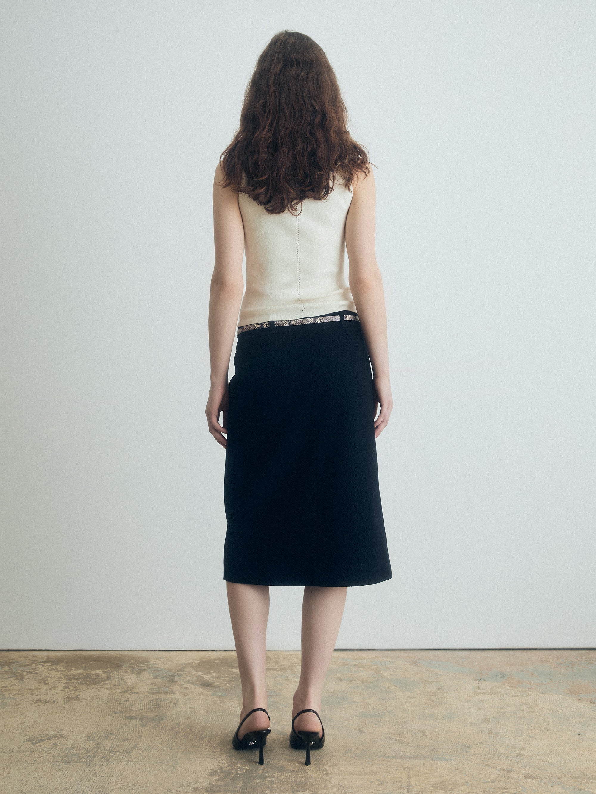 Woman wearing a white top and black skirt against a plain background