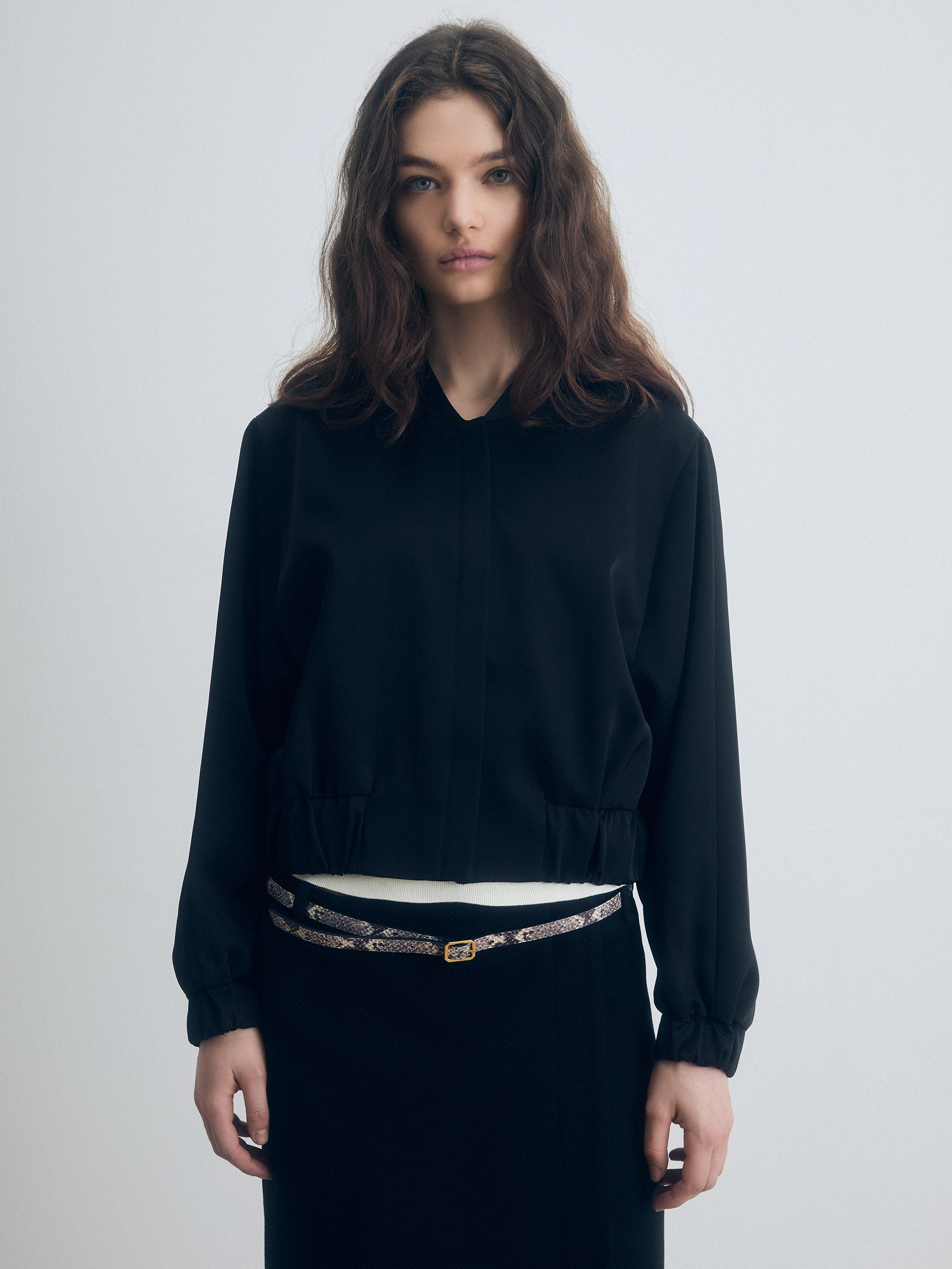 Black zip‑front jacket with elastic hem and cuffs, shown in a clean, structured silhouette.