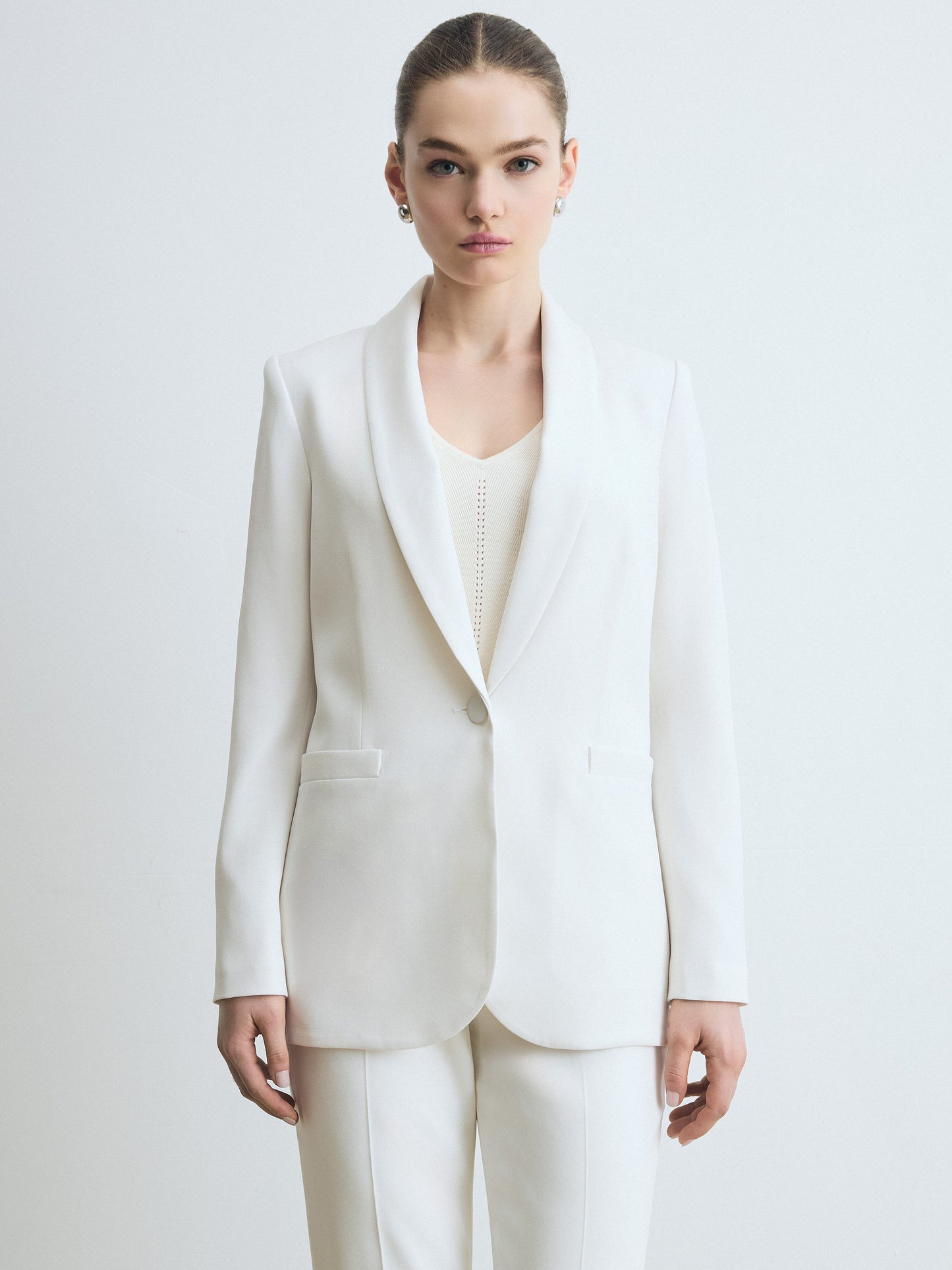 Woman wearing a jacket in satin back crepe with a clean, easy fit. Finished with welt pockets, a self‑covered button, and a single back vent