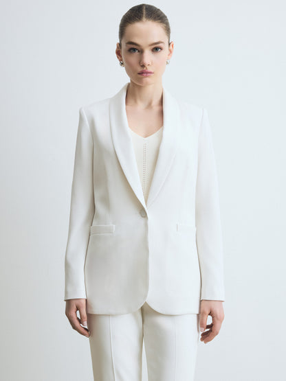 Woman wearing a jacket in satin back crepe with a clean, easy fit. Finished with welt pockets, a self‑covered button, and a single back vent