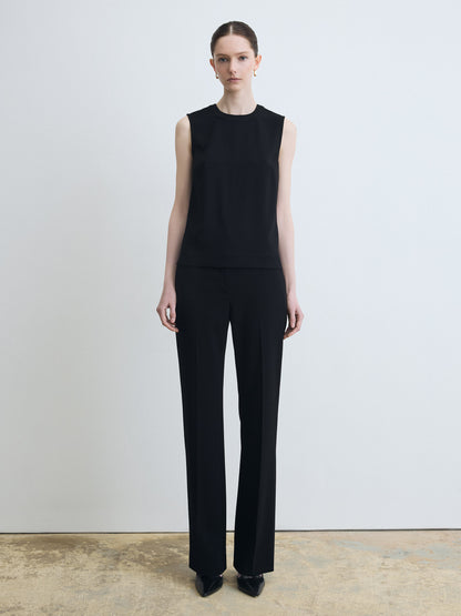 Person wearing a black sleeveless top and black pants on a plain background