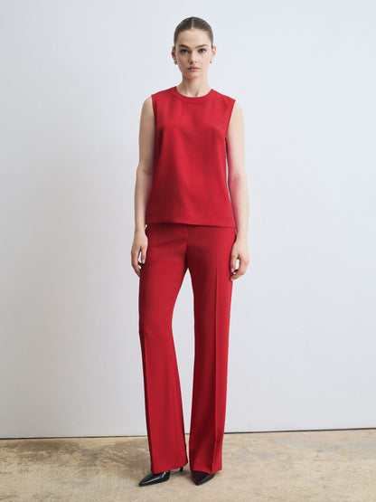 Person wearing a red sleeveless top and pants on a light gray background