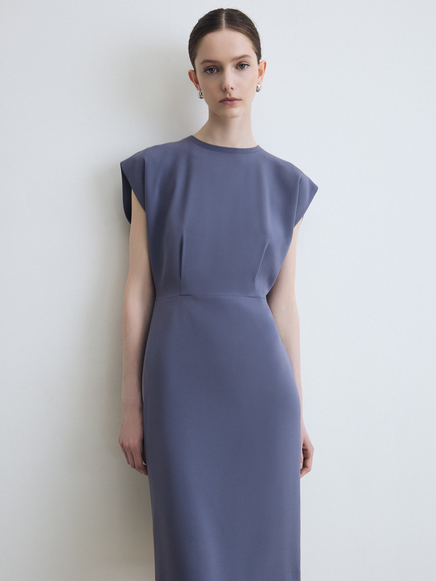 Woman wearing a sleeveless purple dress against a white background