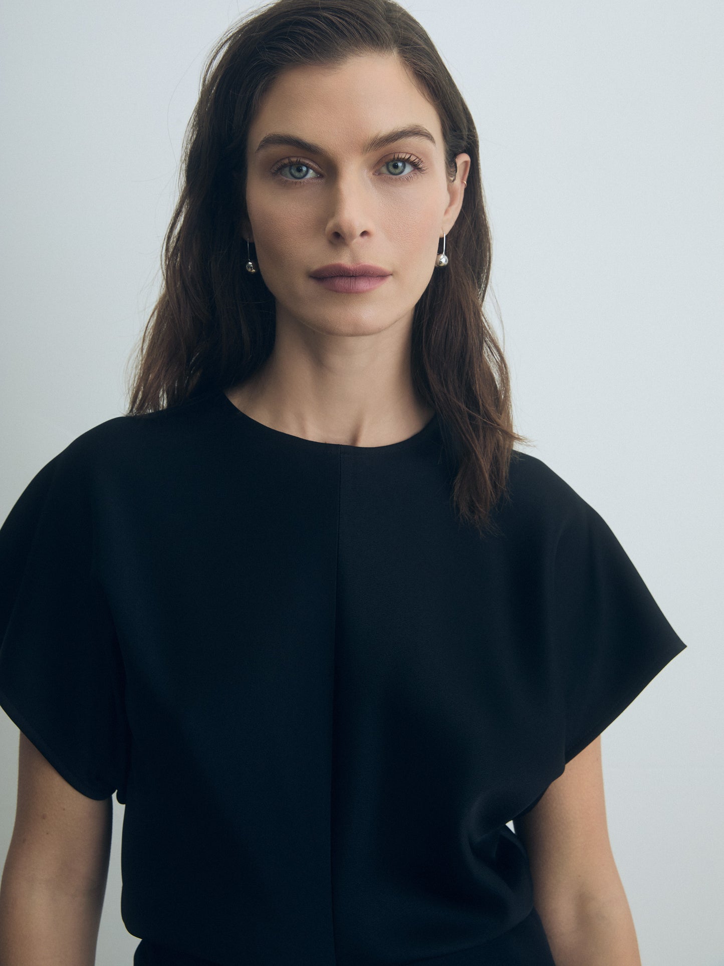 Woman wearing a black top against a plain background