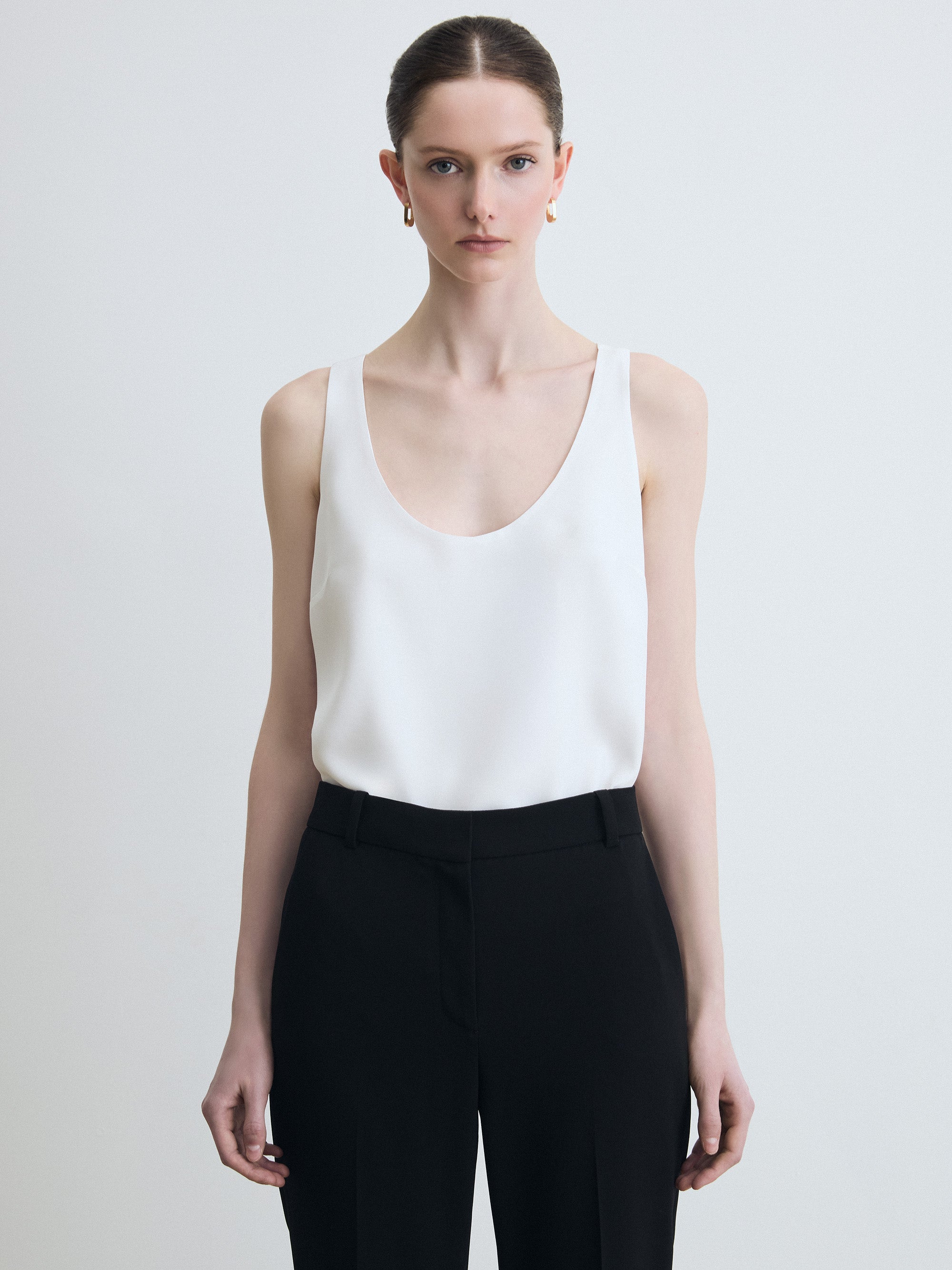 Sleeveless white silk top paired with a black pants