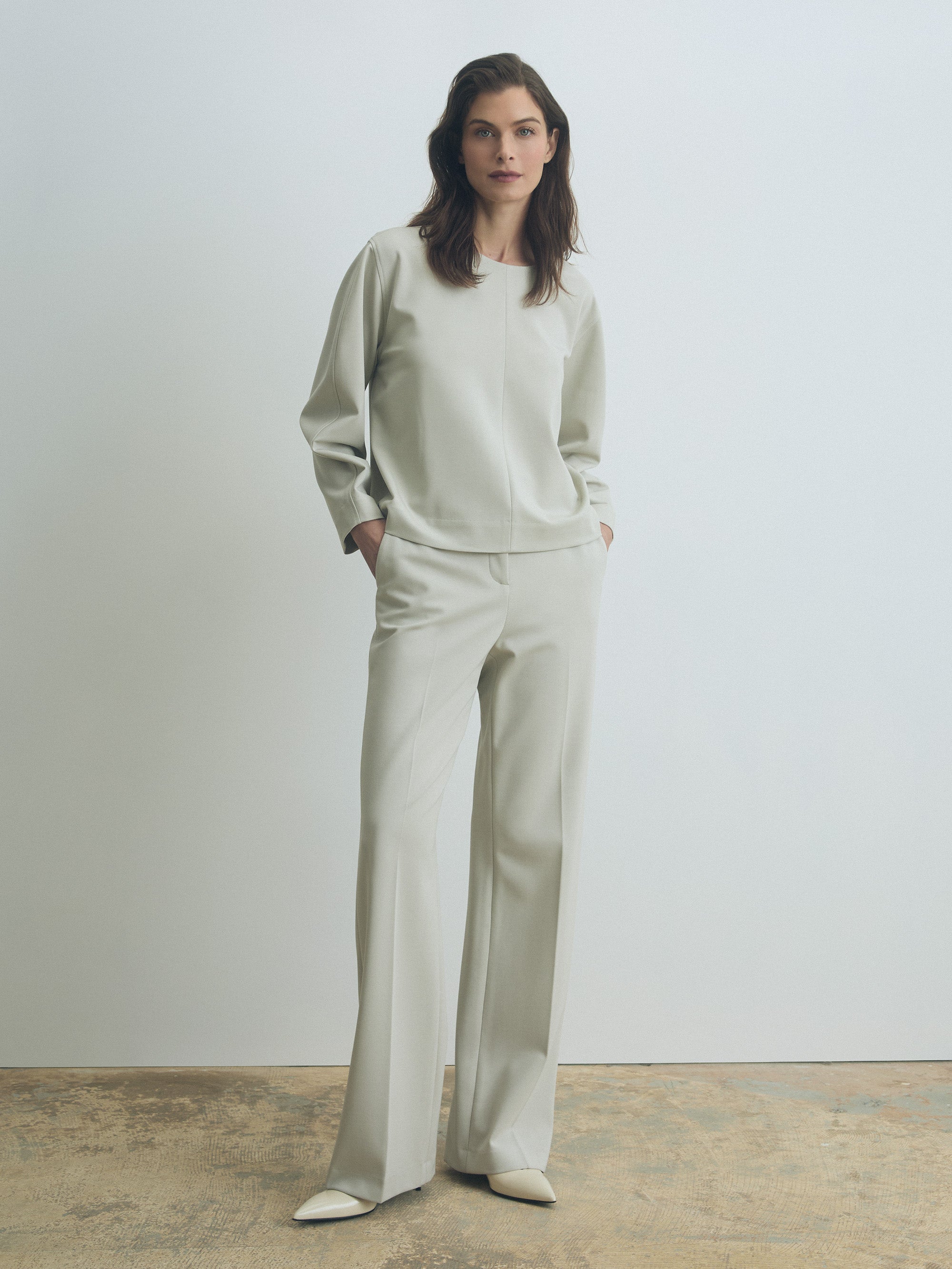 Woman wearing a light gray outfit against a plain background