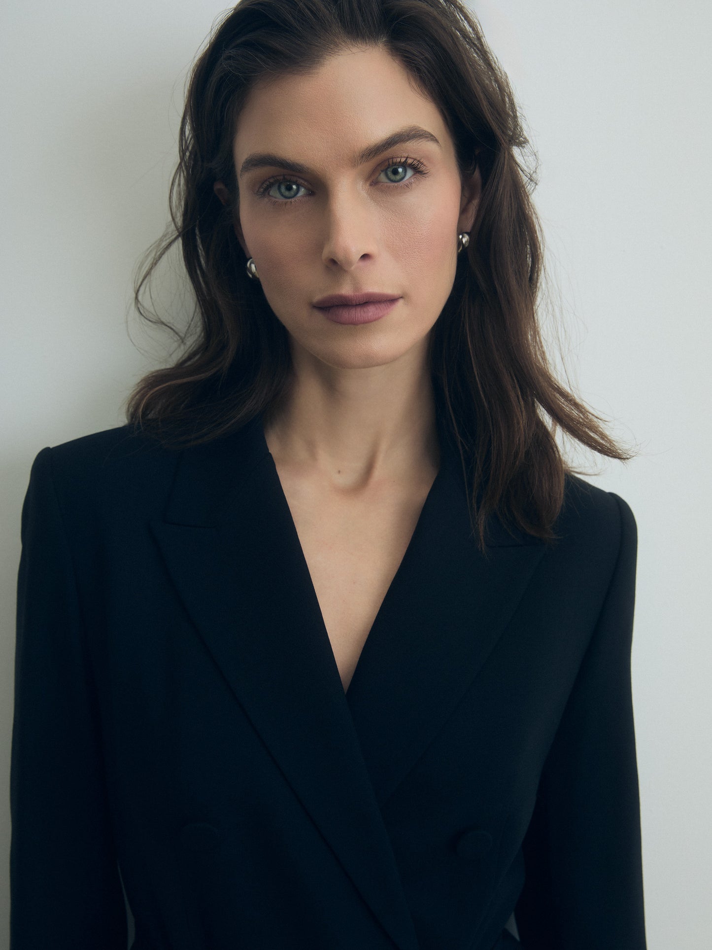 Woman wearing a black double breasted blazer dress against a plain background