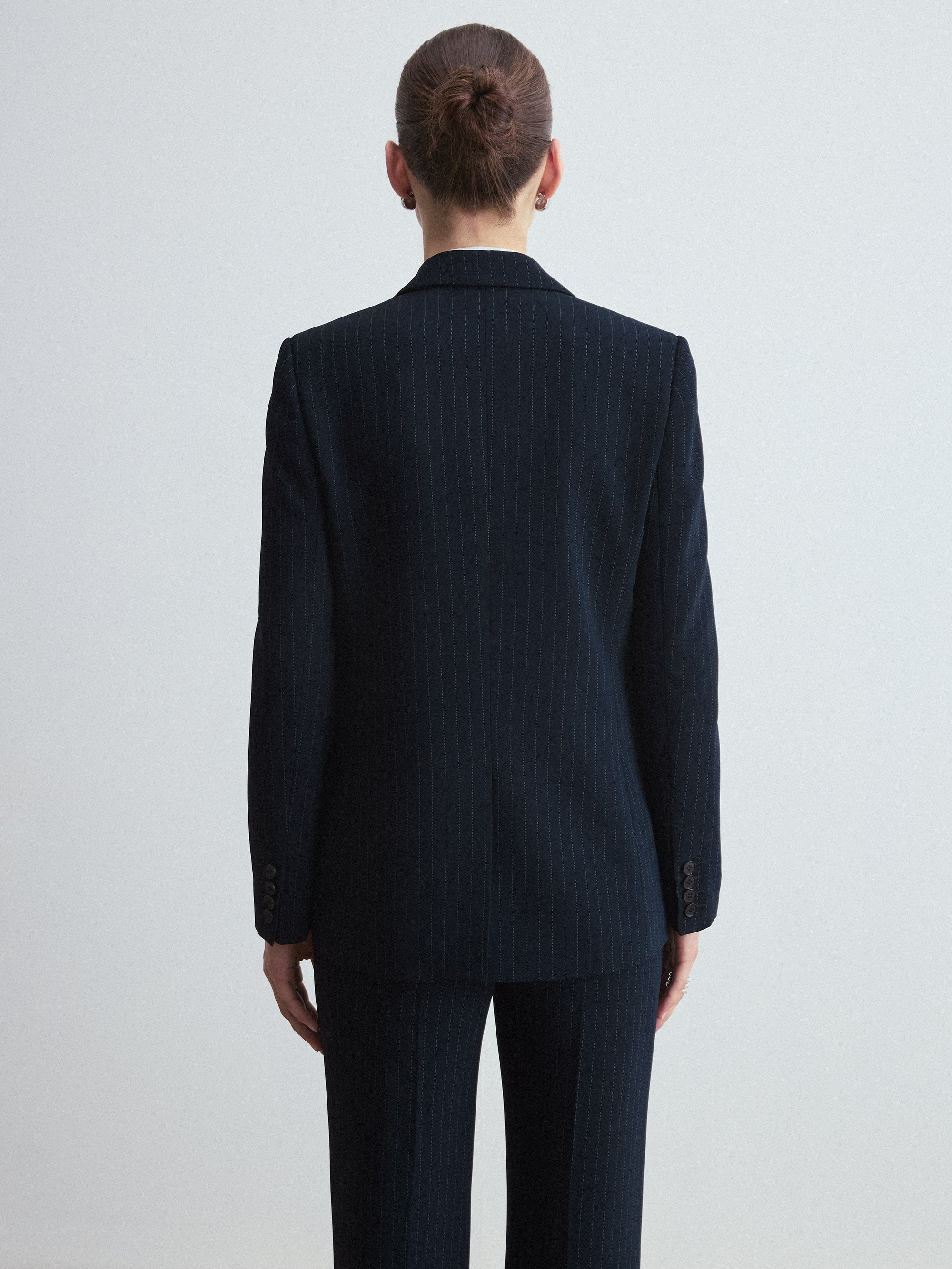 Person wearing a navy pinstripe suit on a light gray background