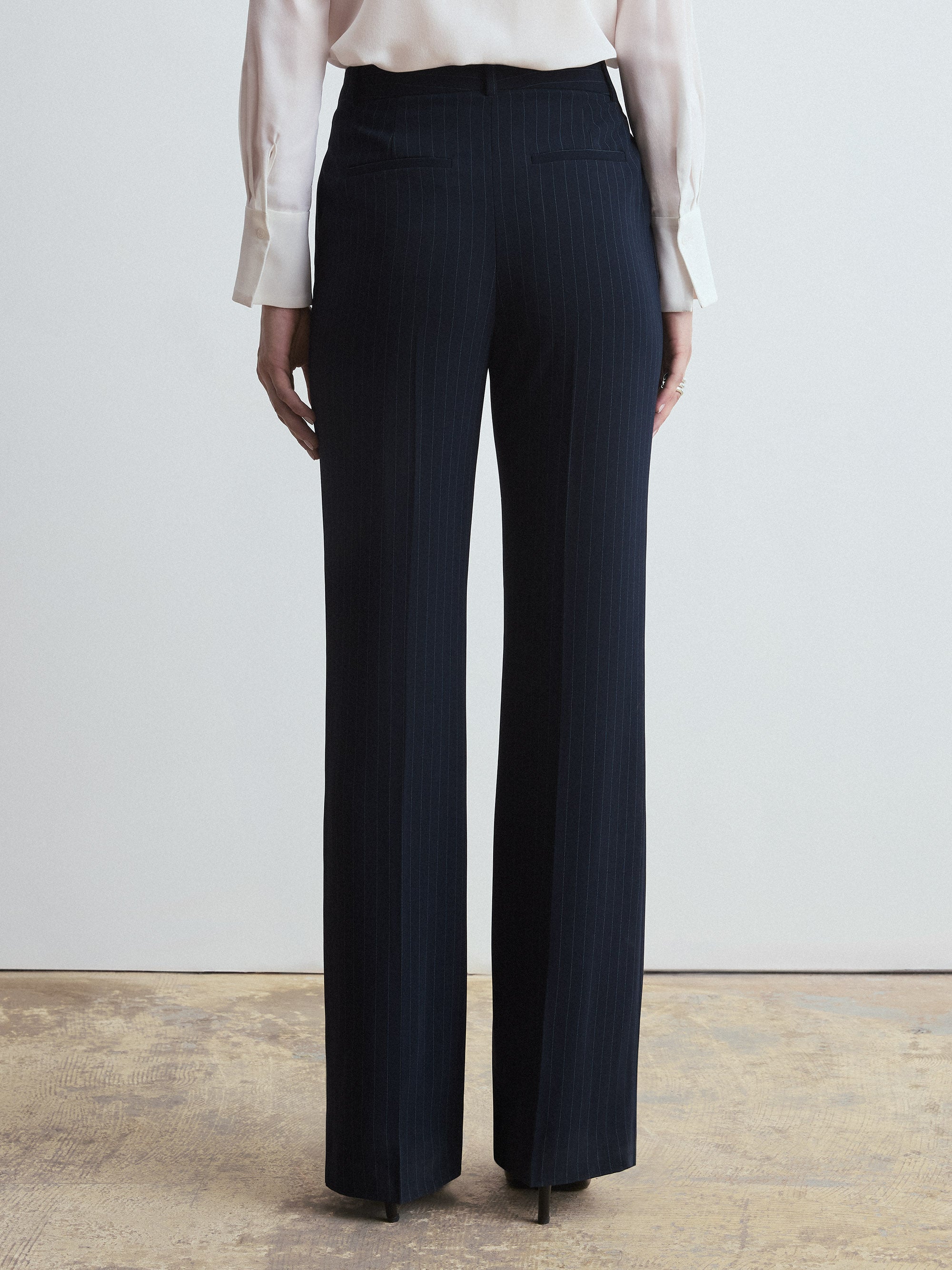 Navy pinstripe pants worn by a person on a plain background