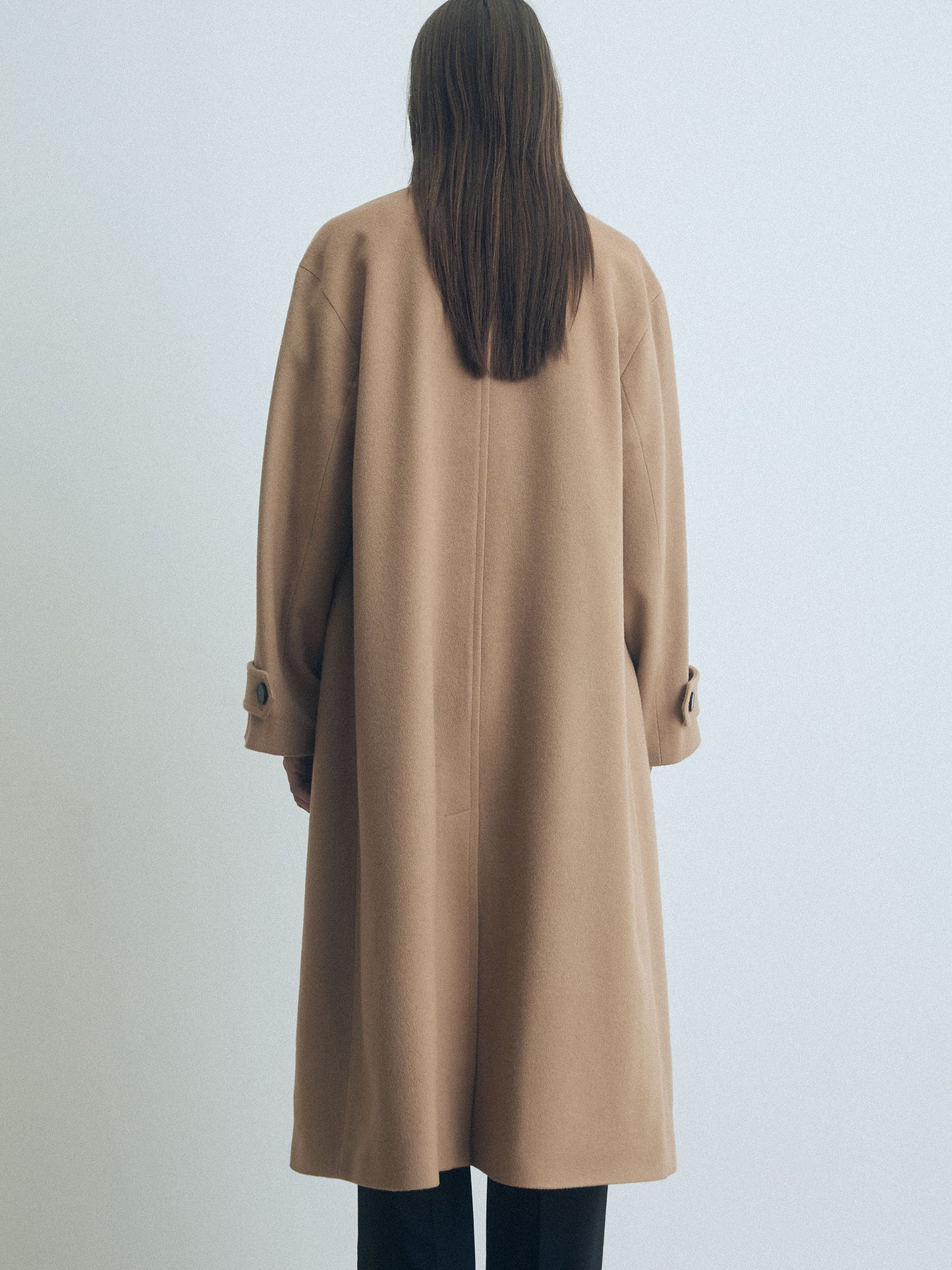 Person wearing a beige coat on a light gray background