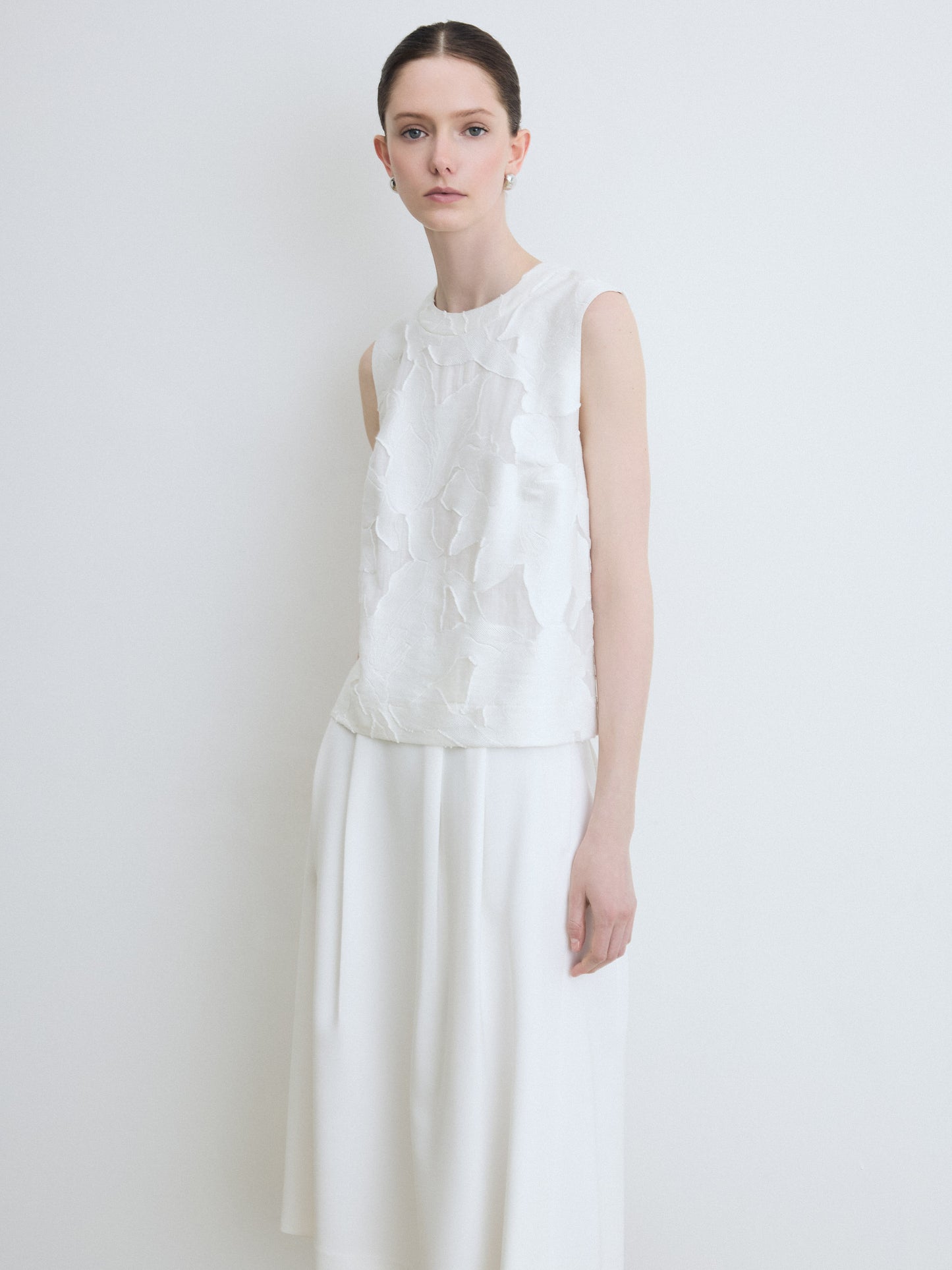Woman wearing a floral white sleeveless top and skirt against a plain background