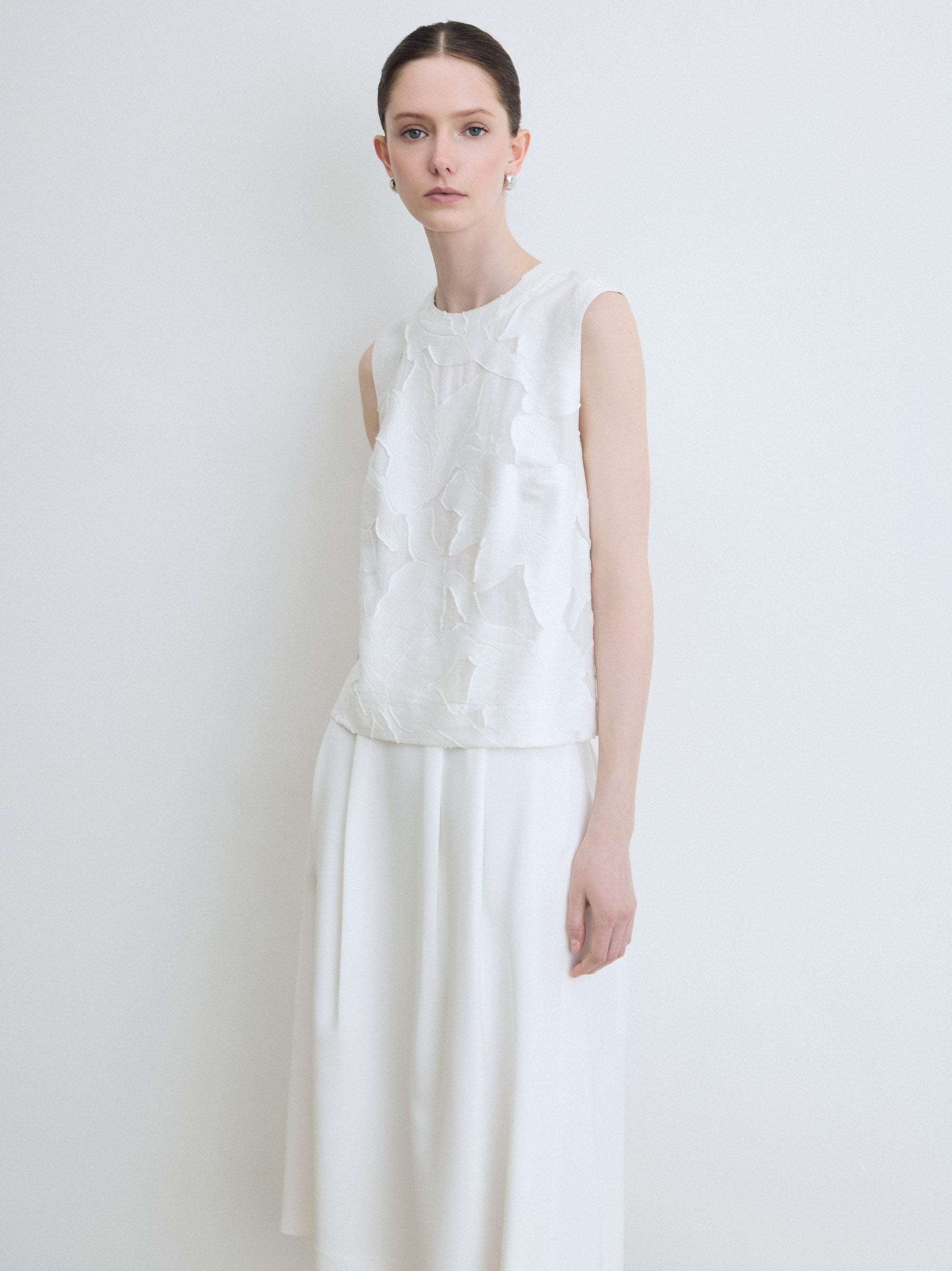 Woman wearing a floral white sleeveless top and skirt against a plain background