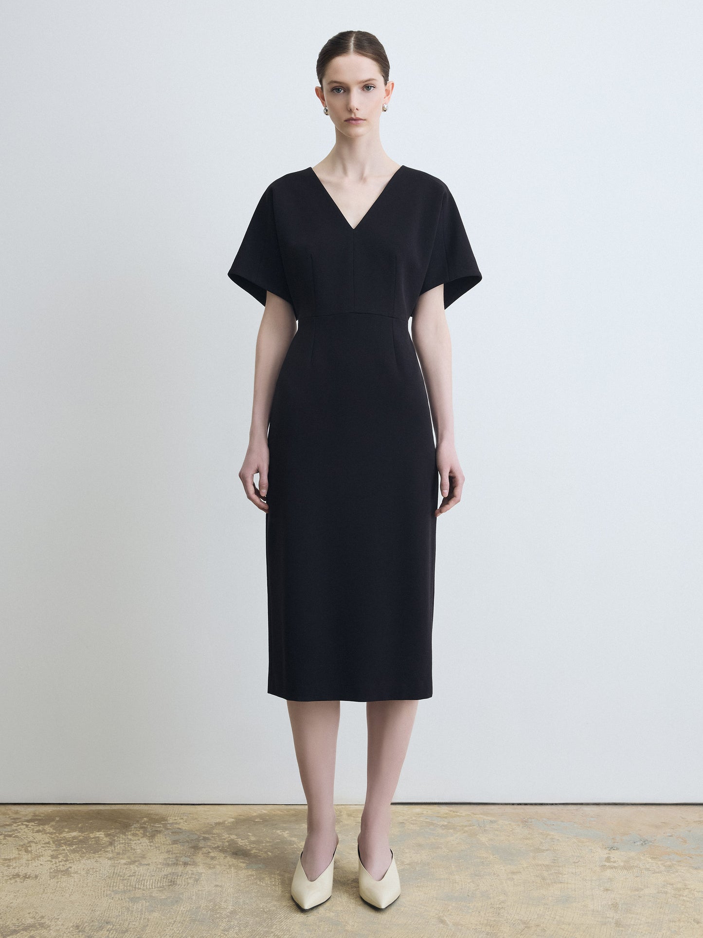 Woman wearing a black dress against a plain background