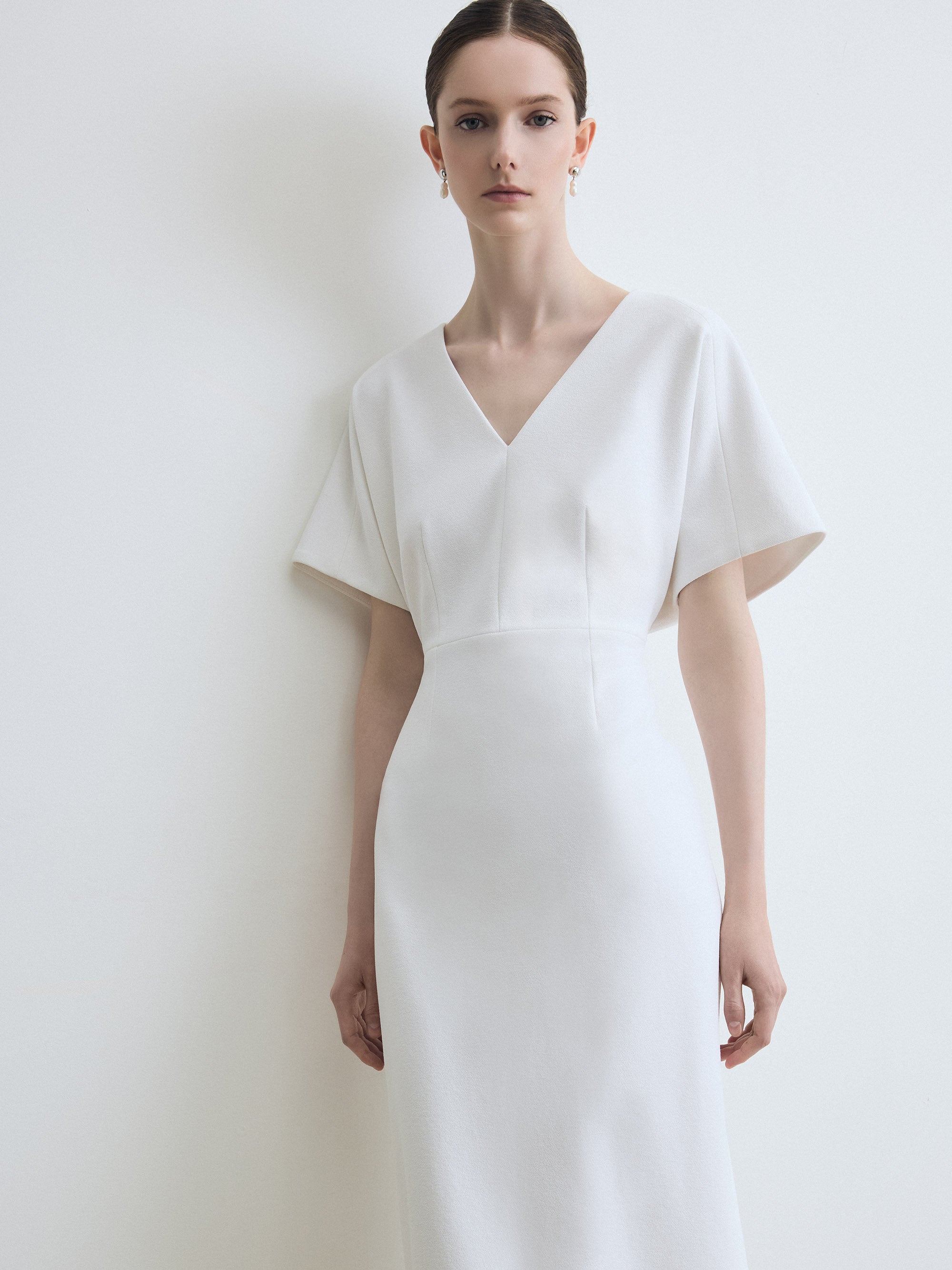 Woman wearing a white dress against a plain background