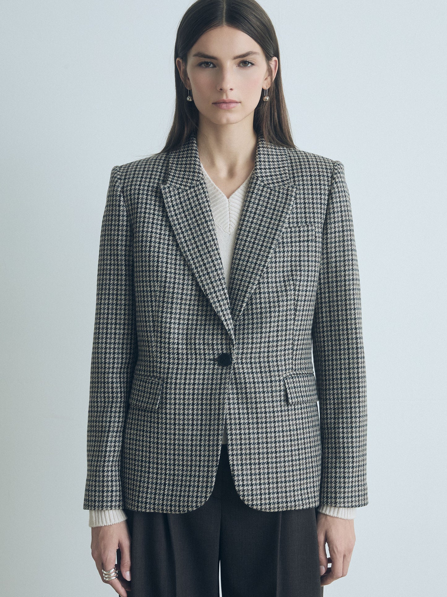 Model wearing the Judith and Charles Verne jacket in grey taupe houndstooth, featuring a tailored fit with peak lapel, front flap pockets, and single-button closure. Styled with matching trousers for a polished, modern look. Made in Canada from a fine Italian wool, silk, and linen blend