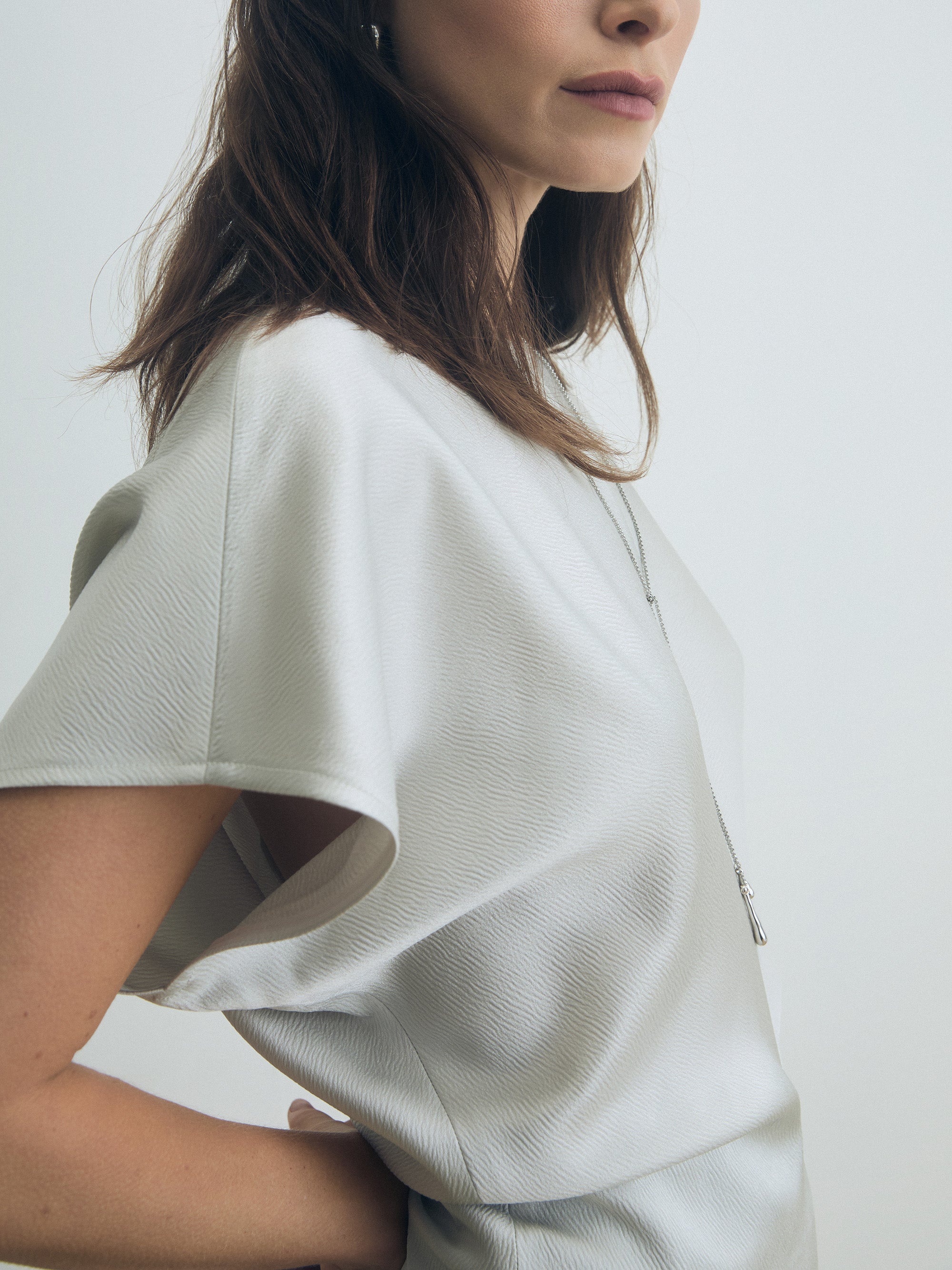 Person wearing a pearl textured shirt against a white background