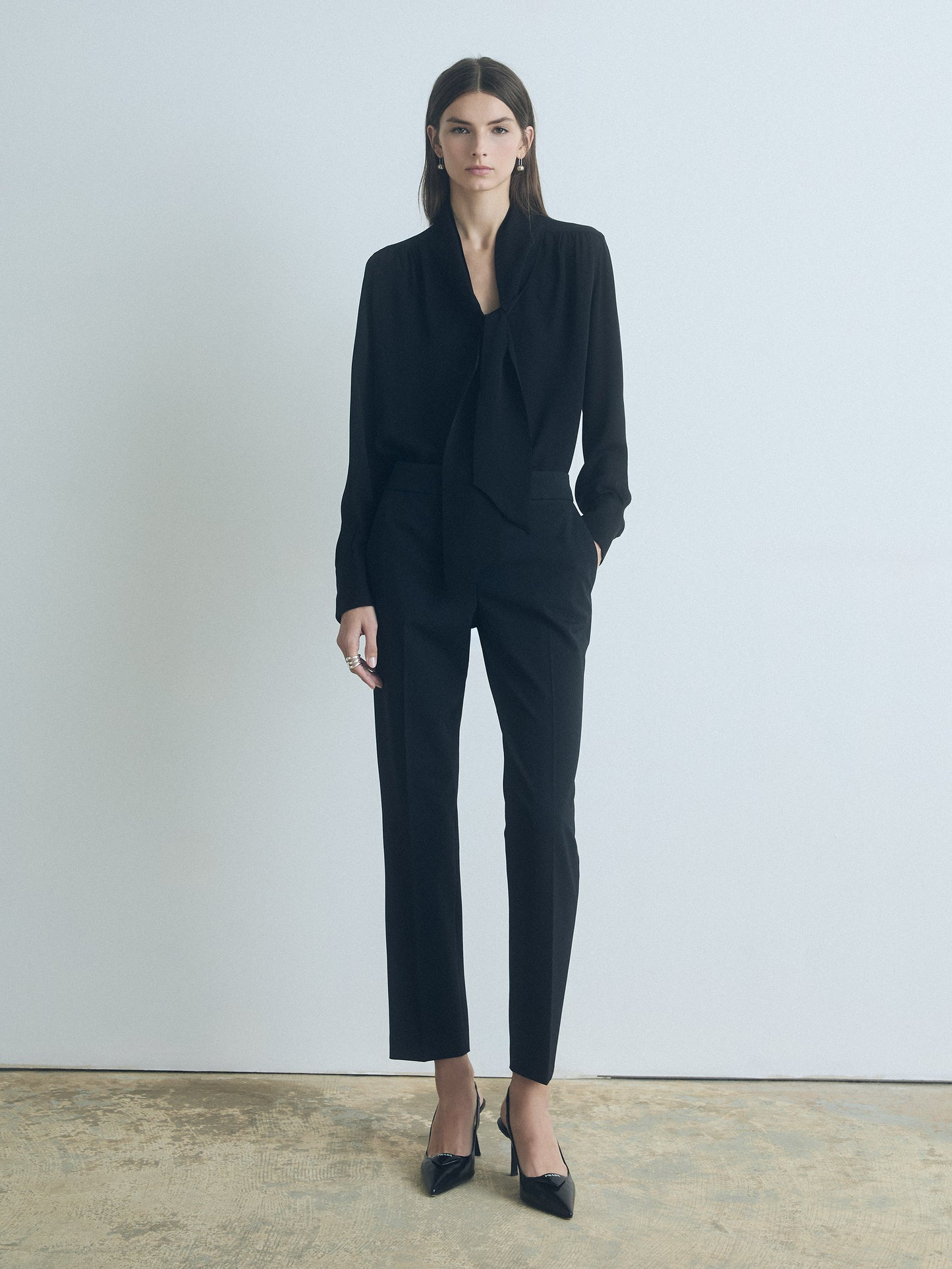 Woman wearing a black suit standing against a plain background
