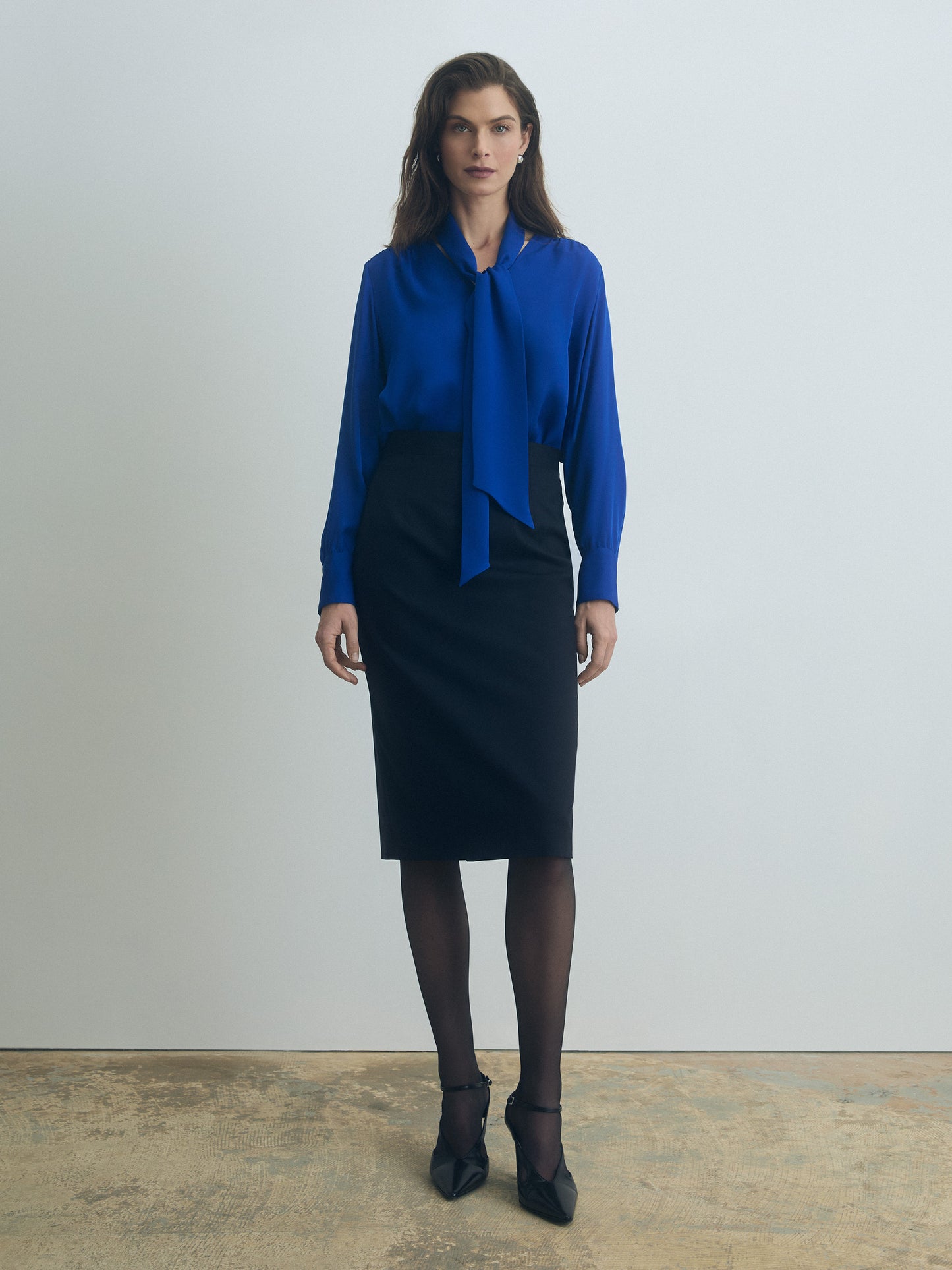 Woman wearing a blue blouse and black skirt against a plain background