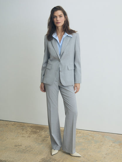 Woman wearing a gray suit with a white shirt against a plain background