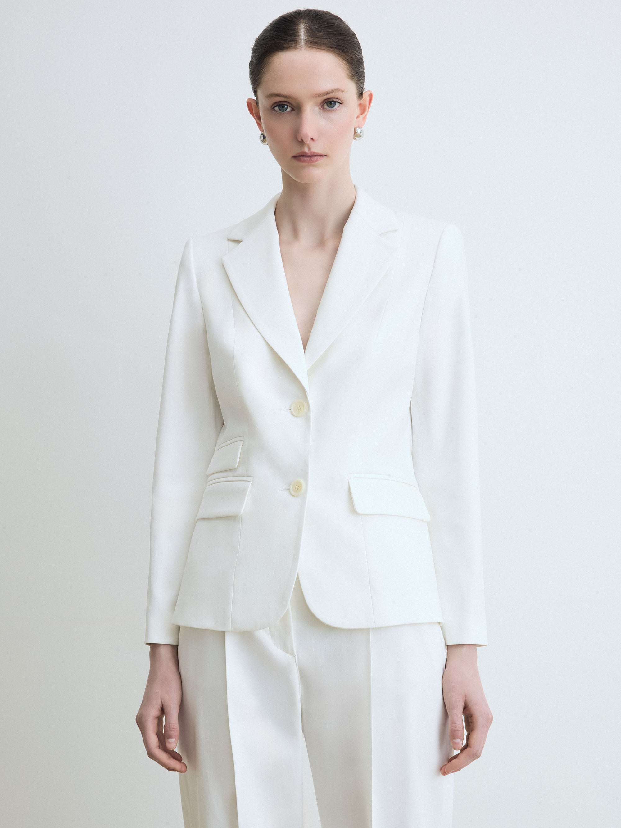 Woman wearing a white suit on a plain background