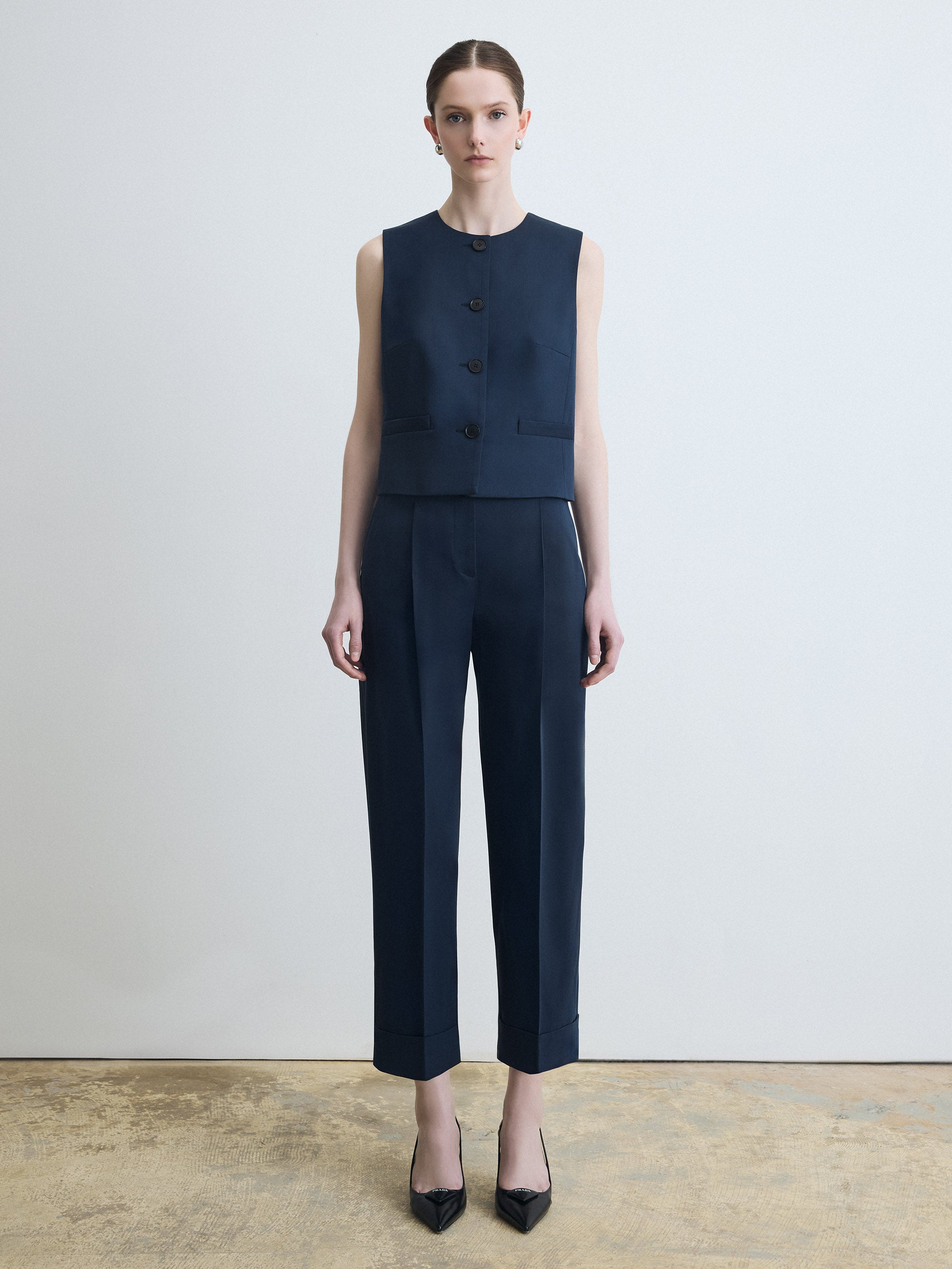 Woman wearing a navy sleeveless top and pants against a white background