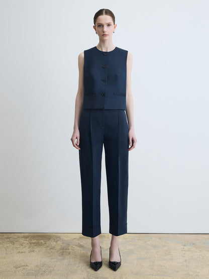 Woman wearing a navy sleeveless top and pants against a white background