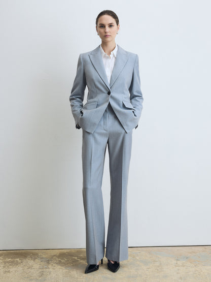 Woman wearing a pale blue suit with a white shirt against a plain background