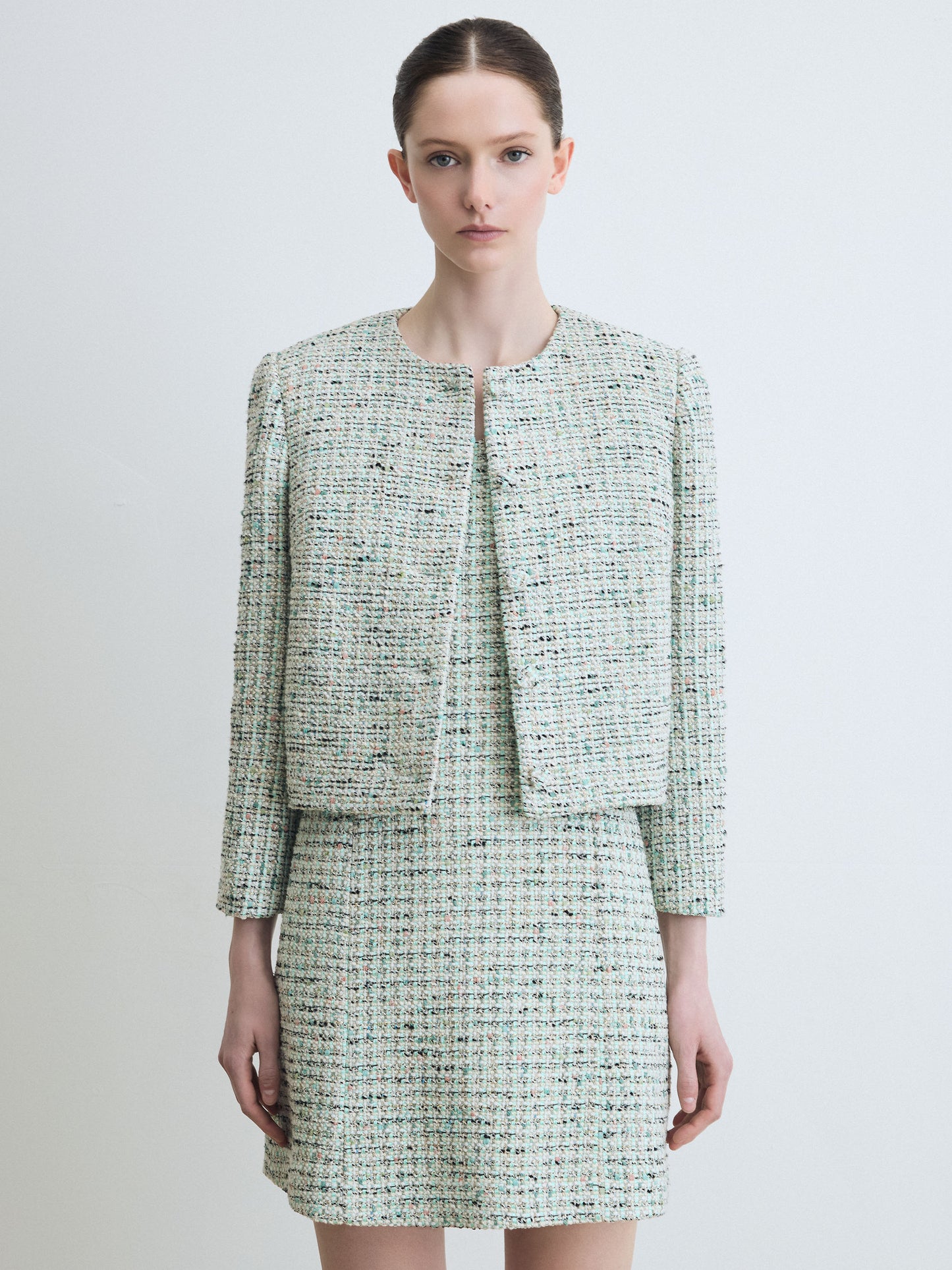 Woman wearing a mint tweed suit on a white background