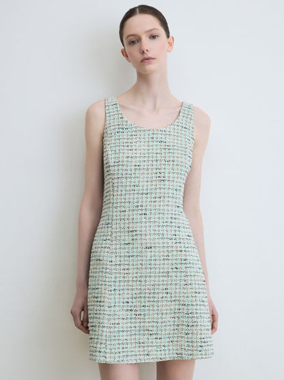 Woman wearing a green sleeveless dress against a white background