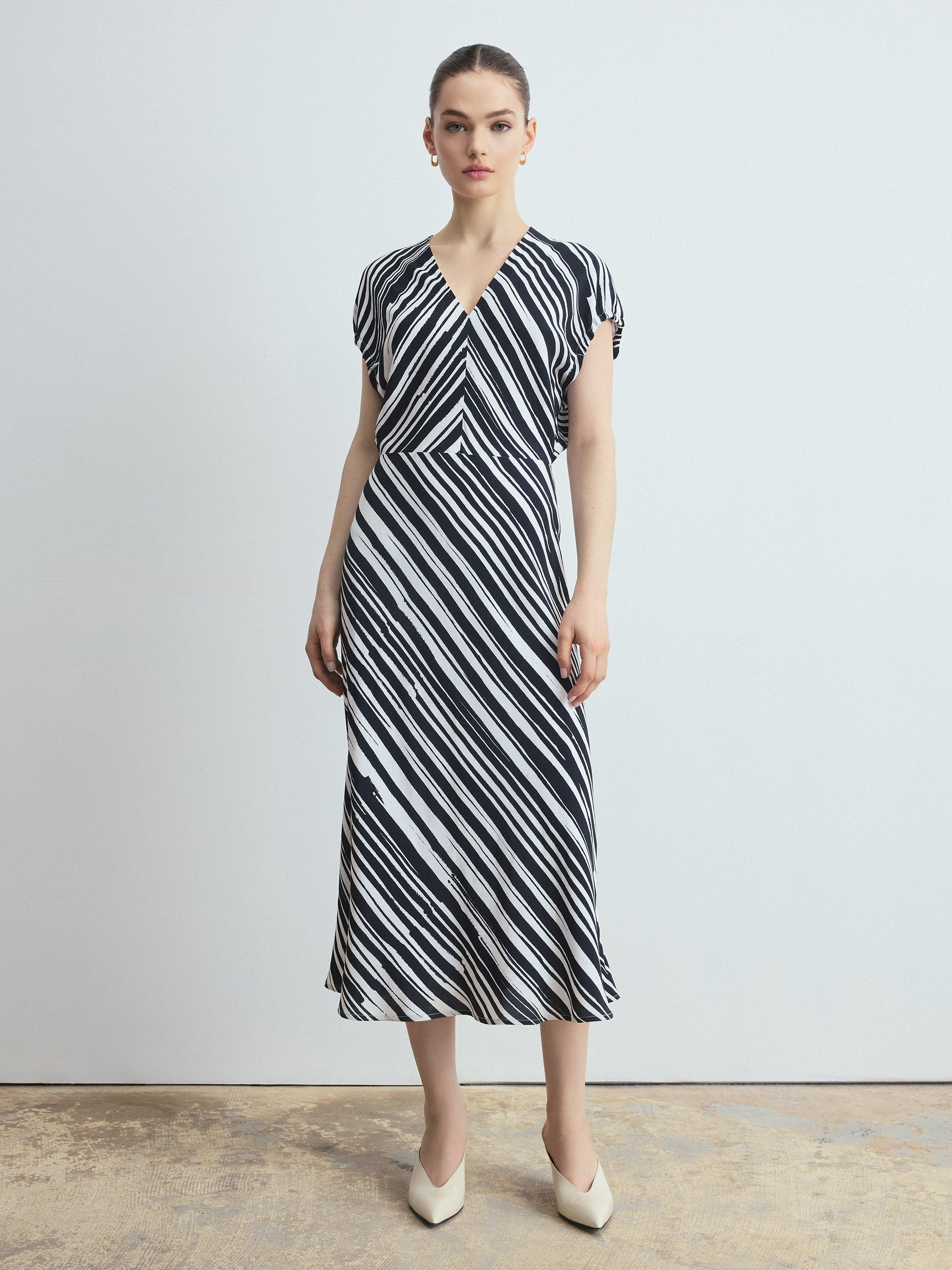 Woman wearing a black and white striped dress against a plain background