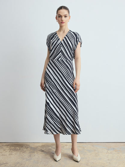 Woman wearing a black and white striped dress against a plain background