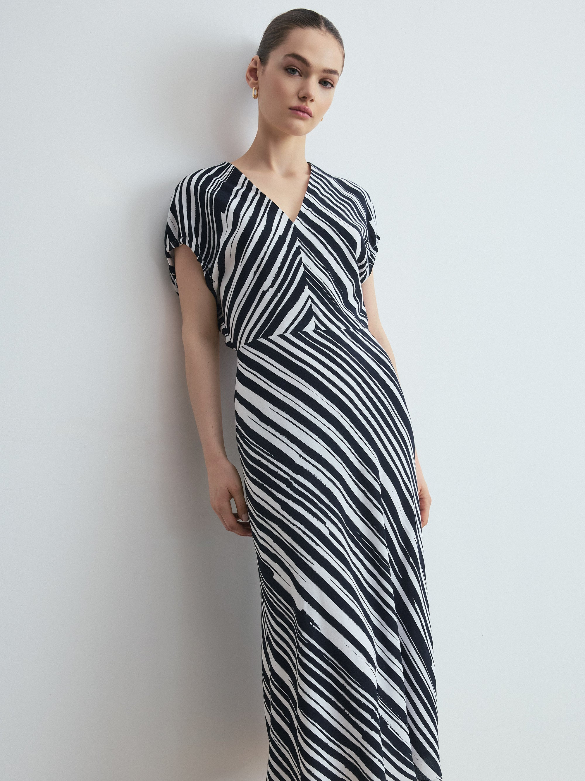 Woman wearing a black and white striped dress against a plain background