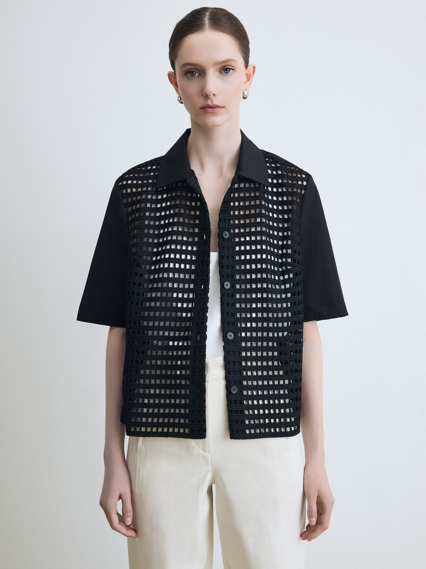 Person wearing a black perforated jacket on a white background