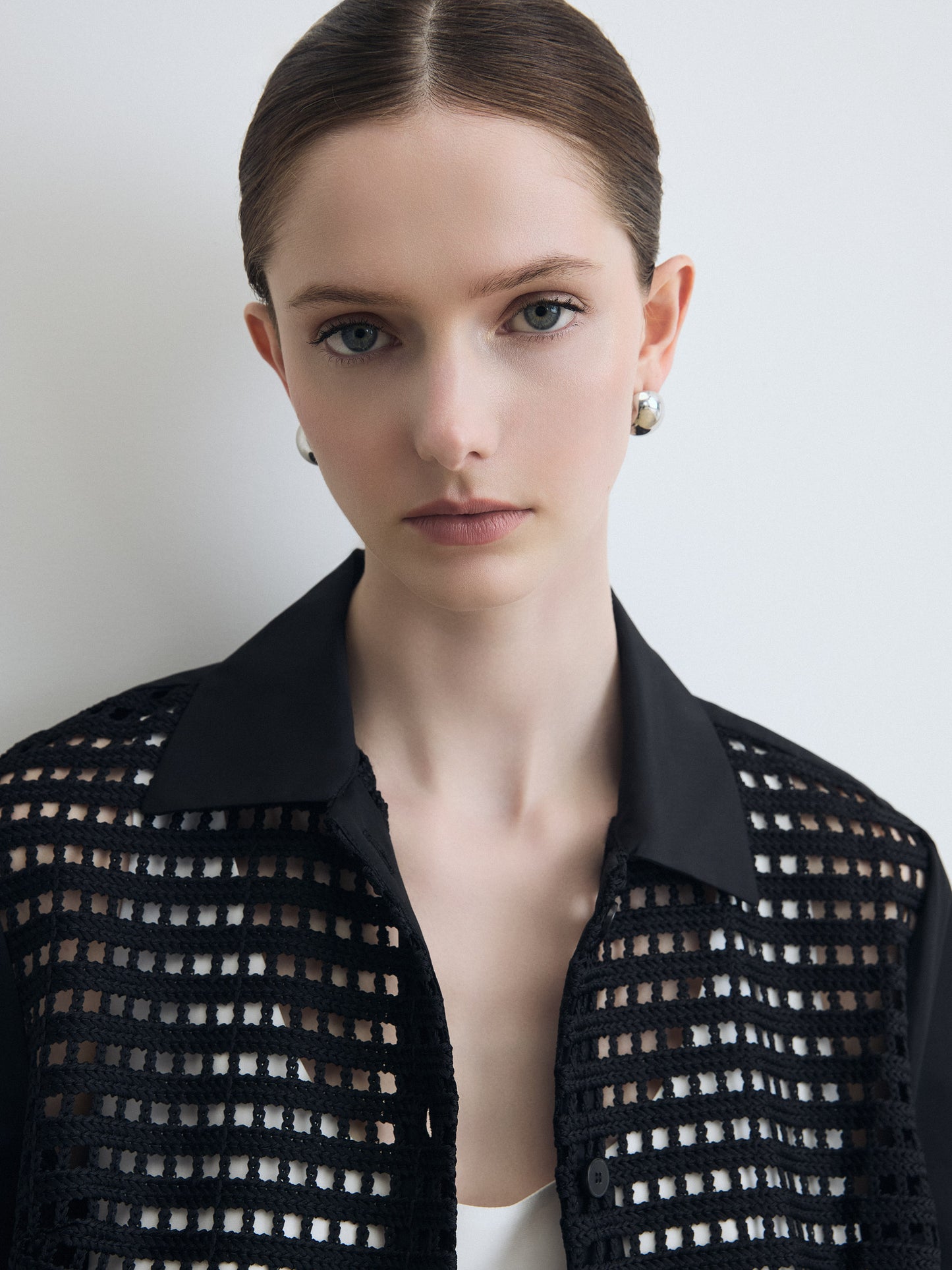 Woman wearing a black mesh top against a plain background