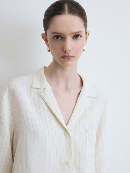 Woman wearing a light-colored blouse against a plain background