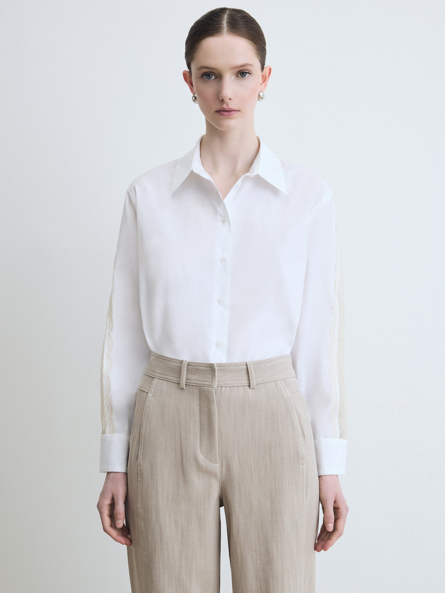 Person wearing a white shirt and beige pants on a plain background