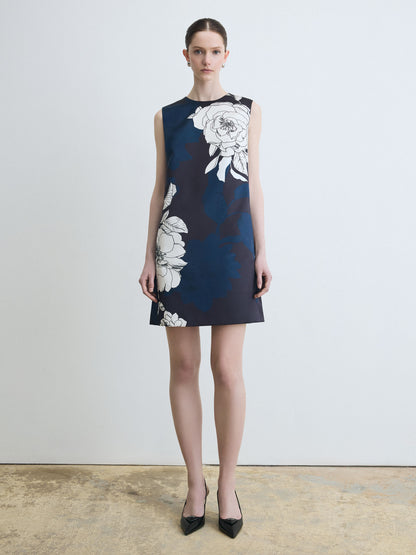 Woman wearing a navy dress with white floral patterns on a plain background